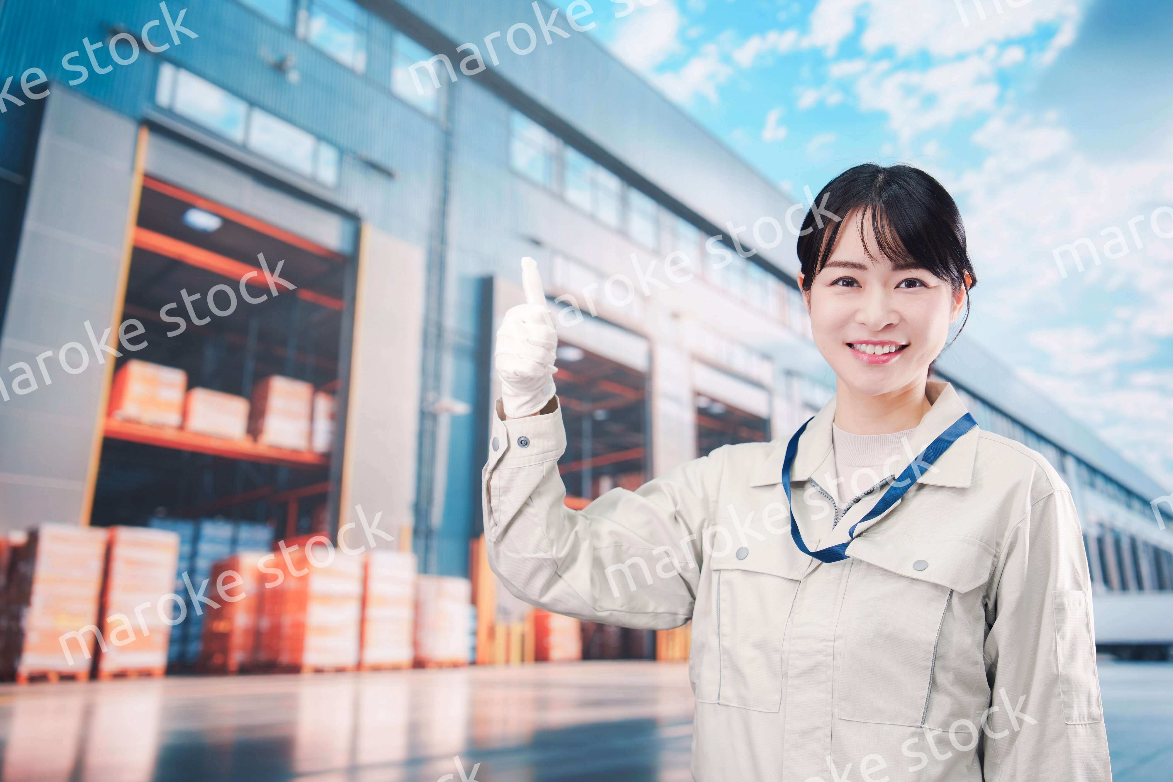 物流拠点で働く作業服姿の若い女性