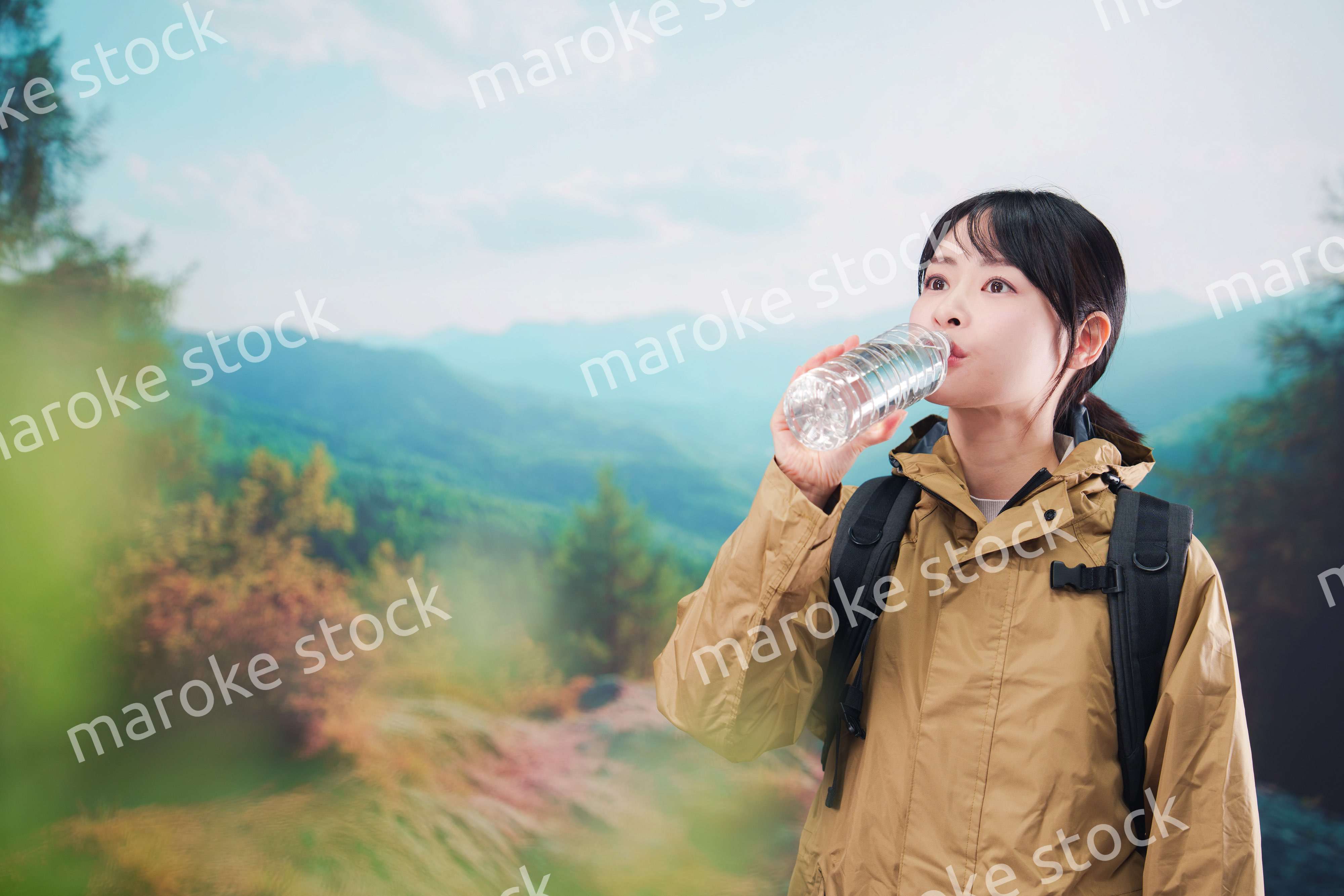 登山をしながら水分補給をする若い女性