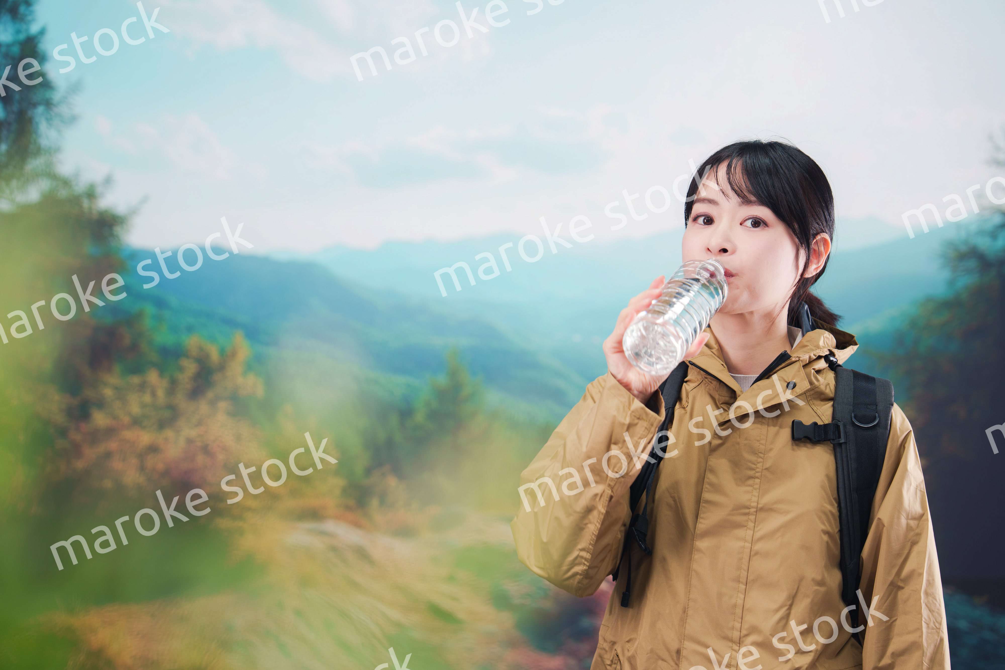 登山をしながら水分補給をする若い女性