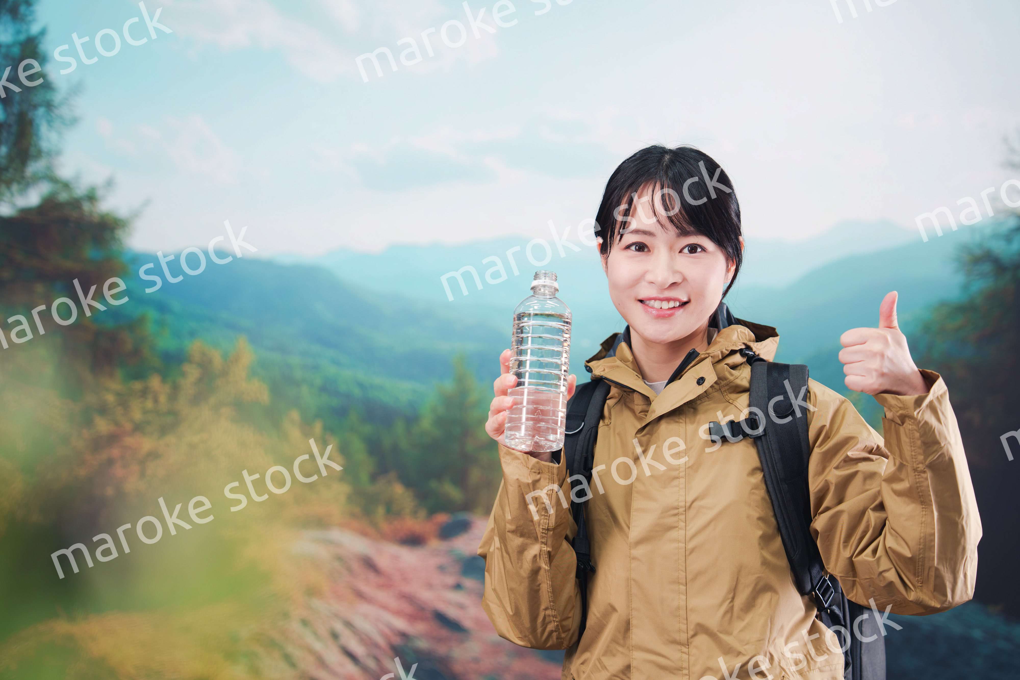 登山をしながら水分補給をする若い女性