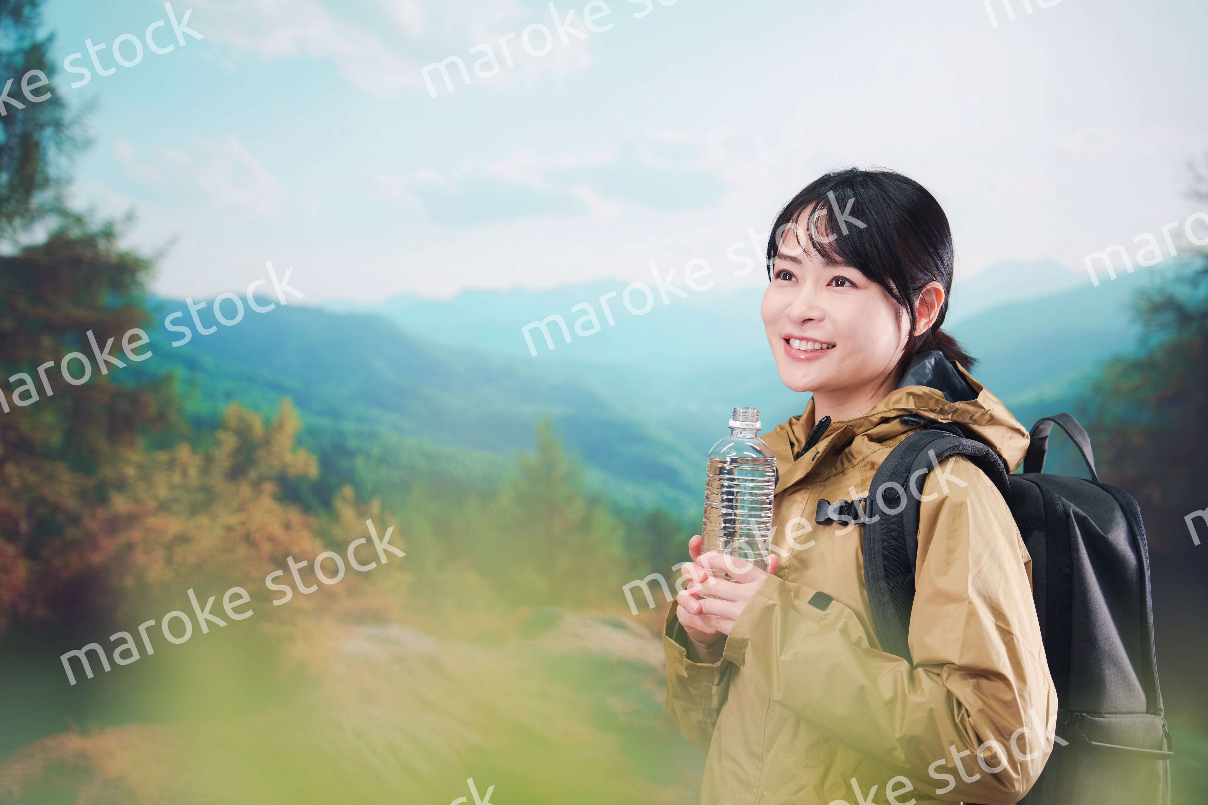 登山をしながら水分補給をする若い女性