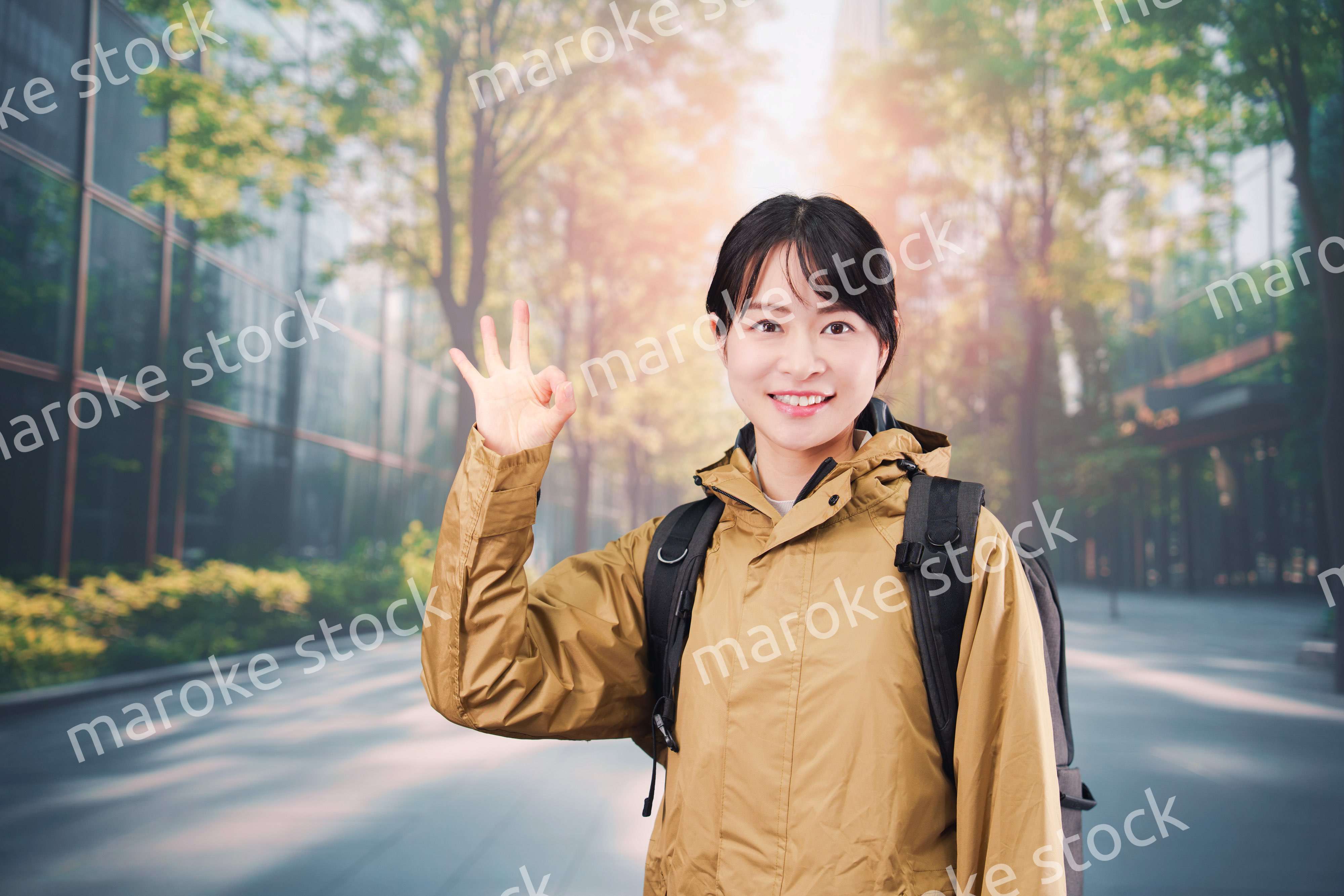 レインコートを着て通勤をする若い女性会社員