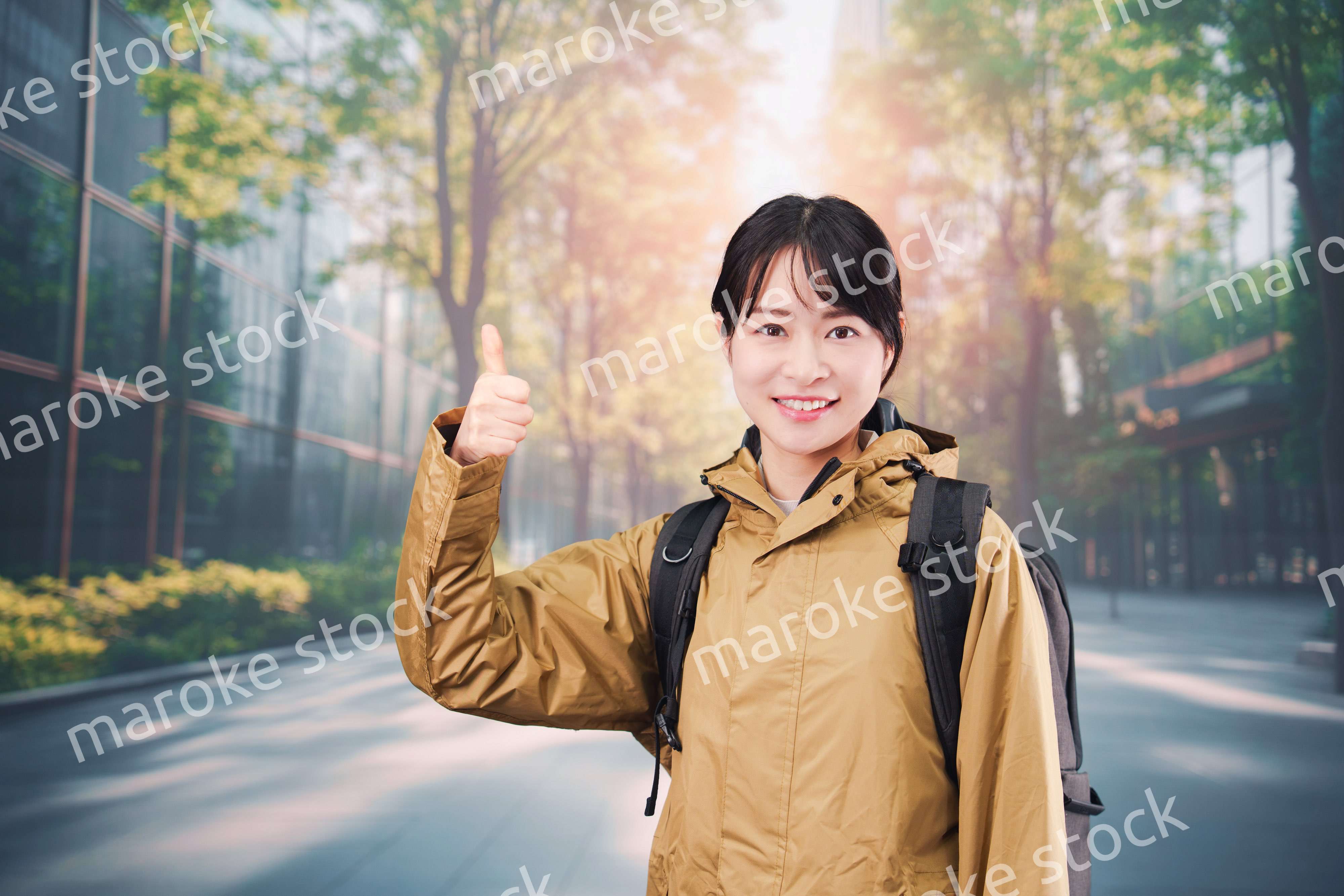 レインコートを着て通勤をする若い女性会社員