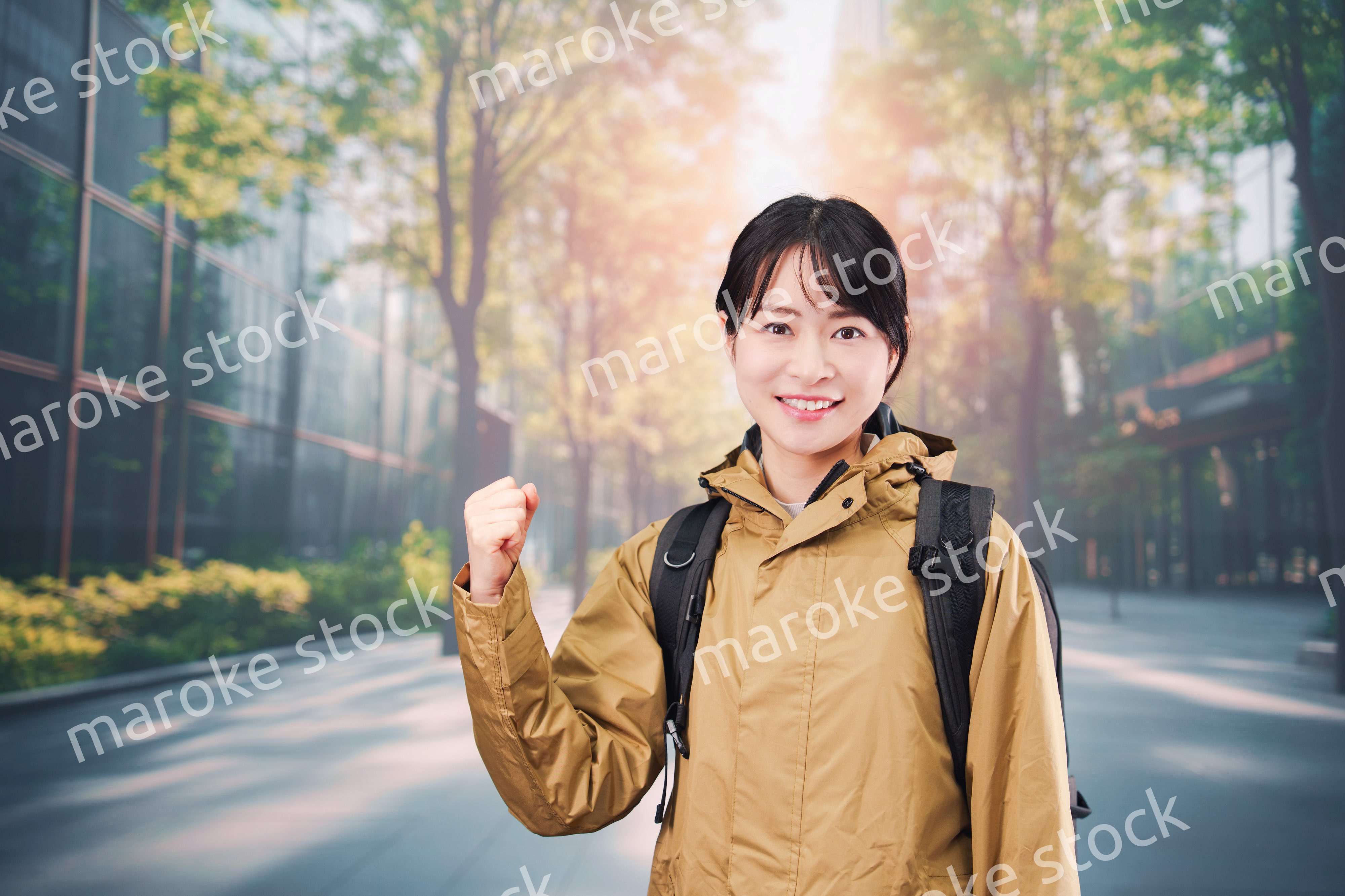 レインコートを着て通勤をする若い女性会社員