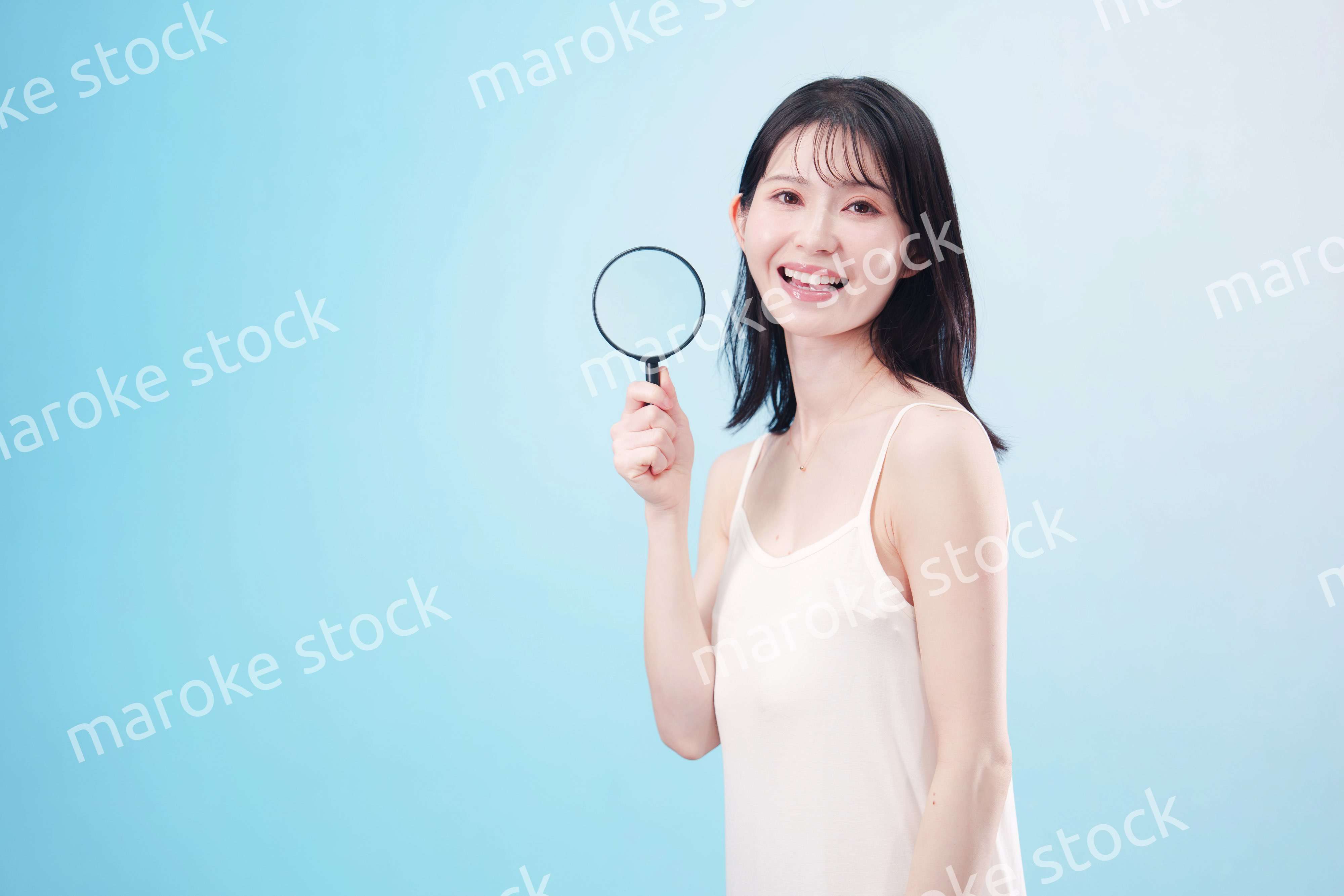 虫眼鏡を持つ若い女性・ビューティーイメージ