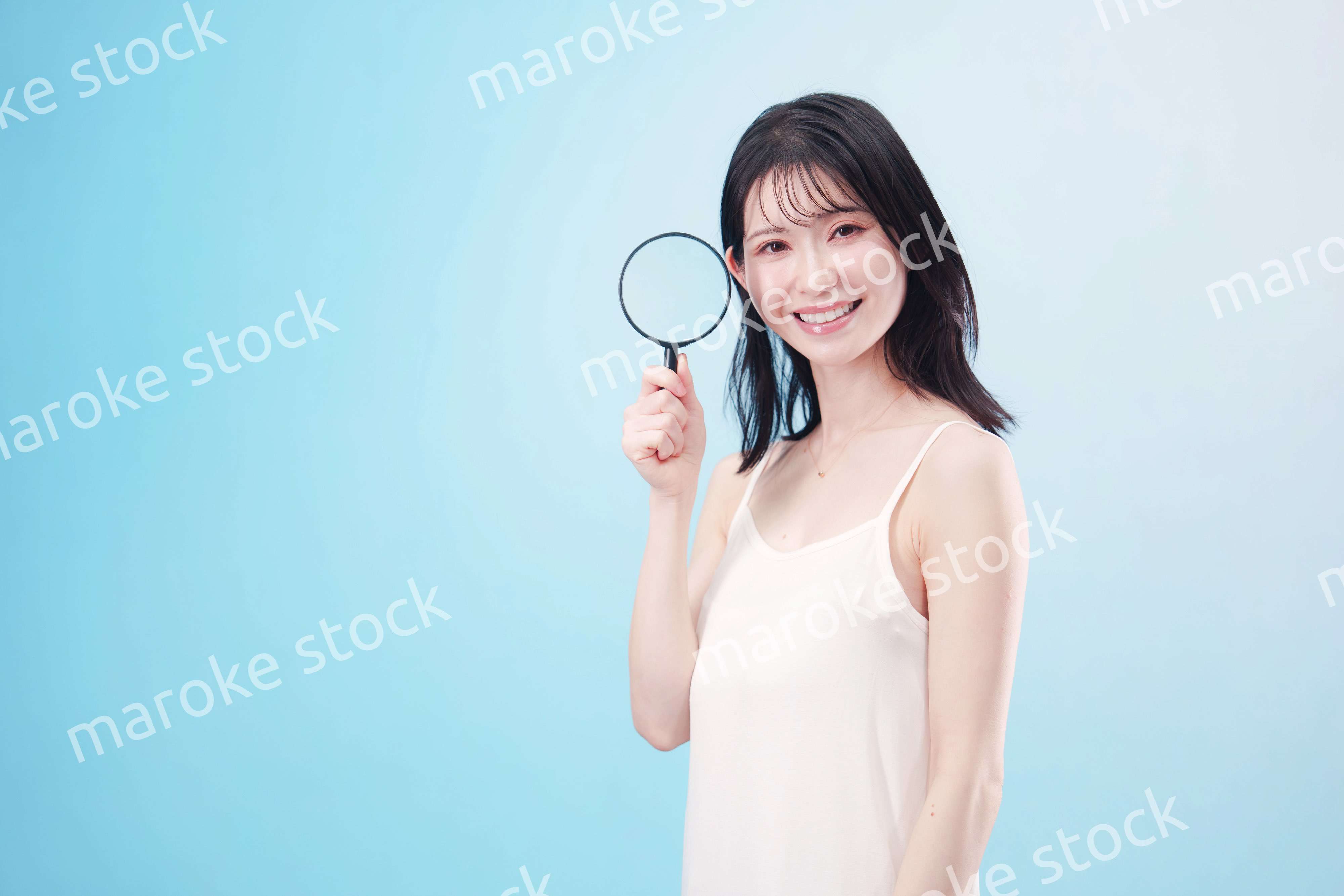 虫眼鏡を持つ若い女性・ビューティーイメージ