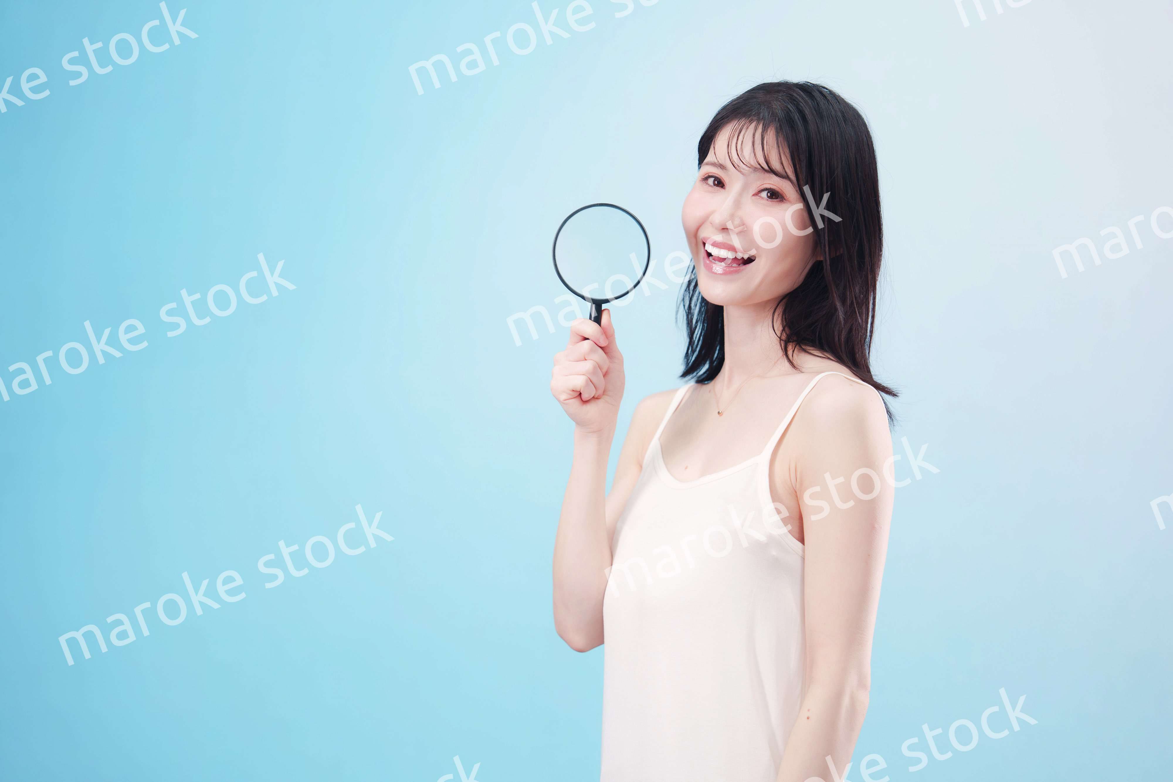 虫眼鏡を持つ若い女性・ビューティーイメージ