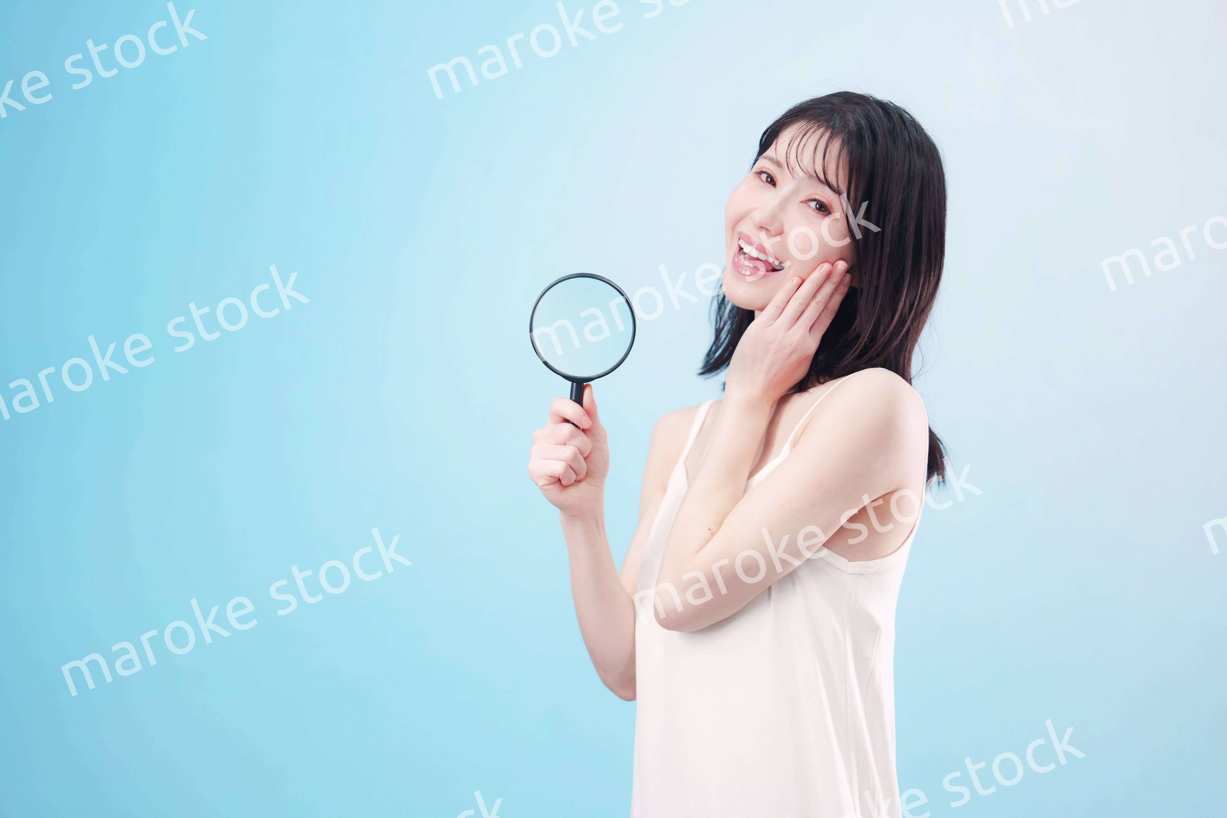 虫眼鏡を持つ若い女性・ビューティーイメージ