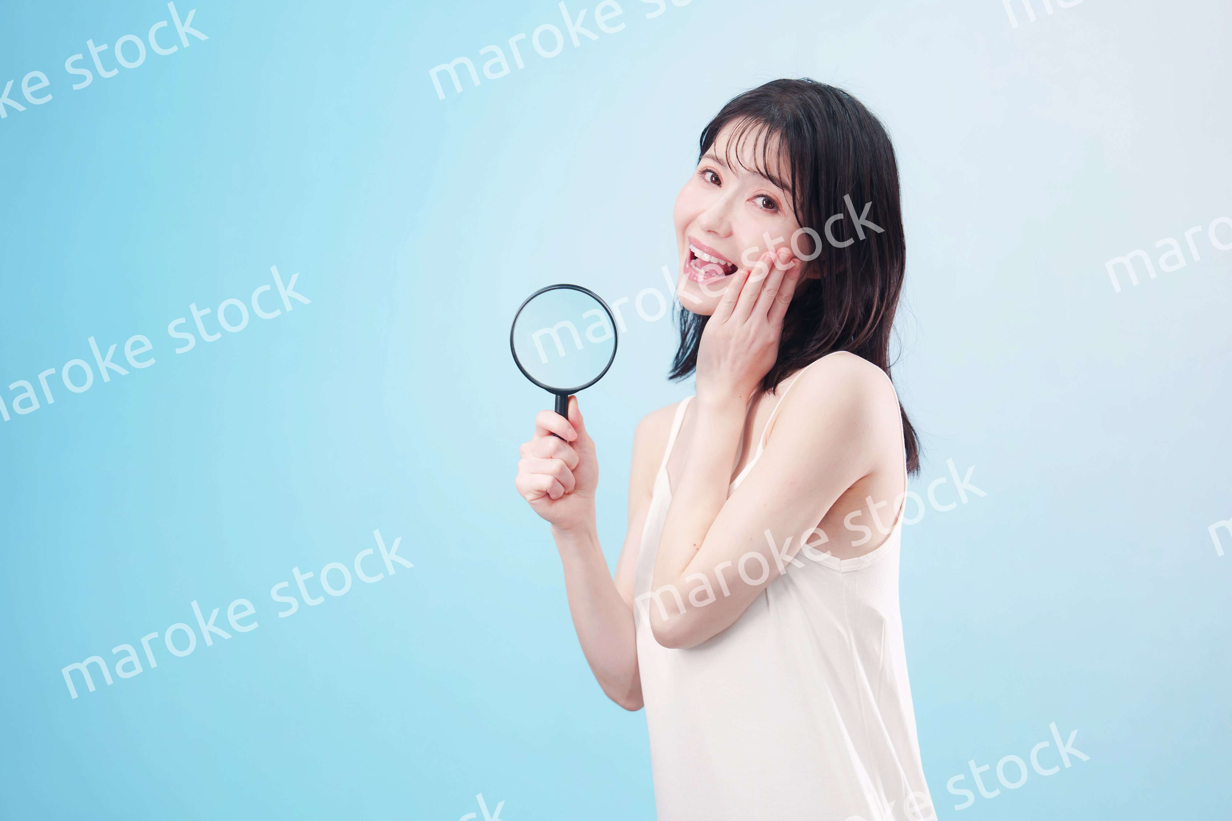 虫眼鏡を持つ若い女性・ビューティーイメージ