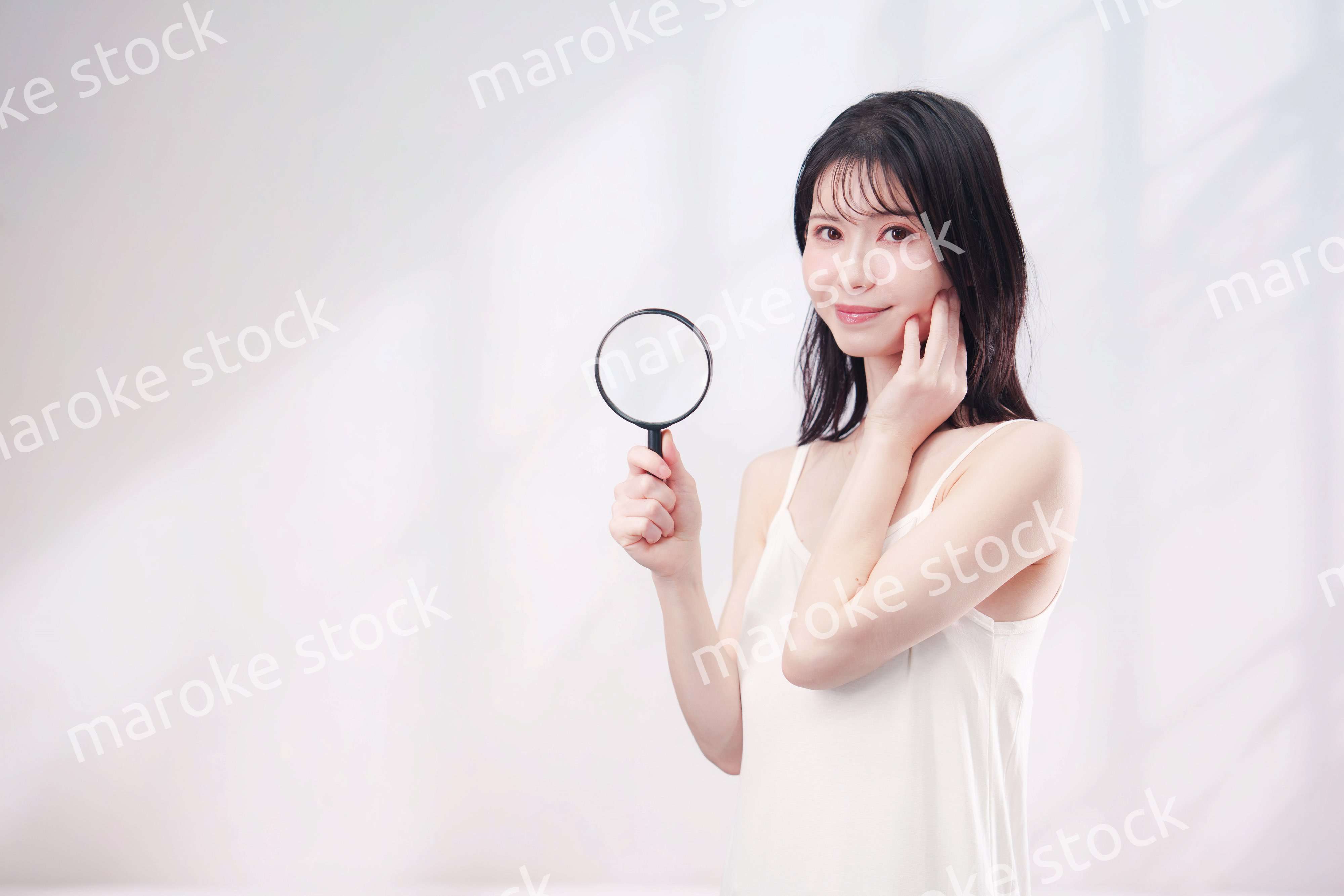 虫眼鏡を持つ若い女性・ビューティーイメージ