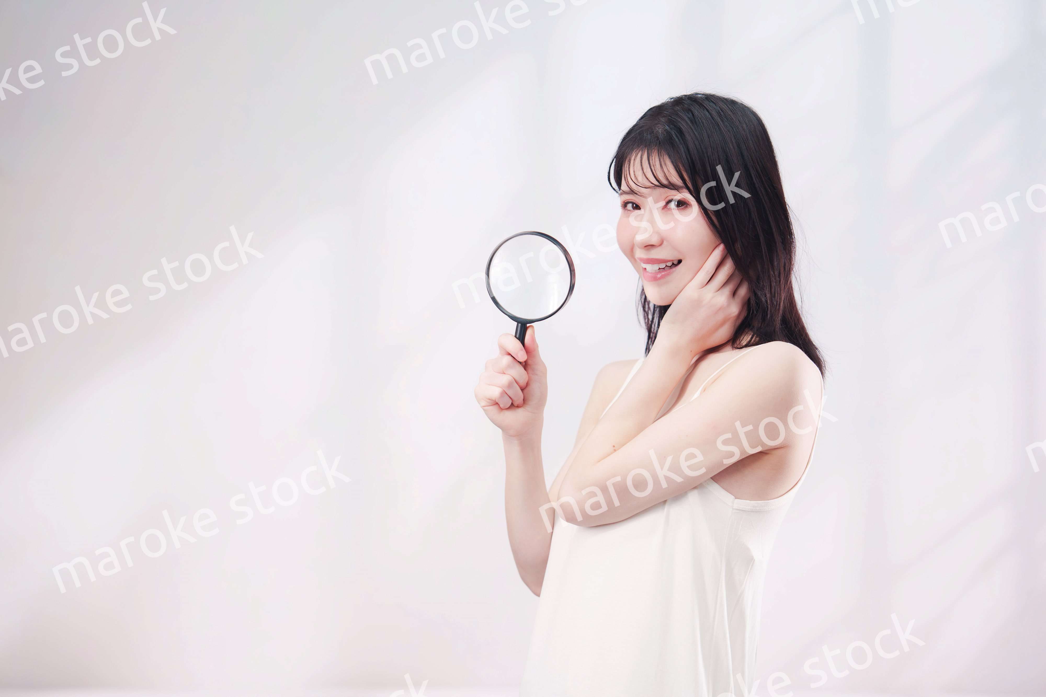 虫眼鏡を持つ若い女性・ビューティーイメージ