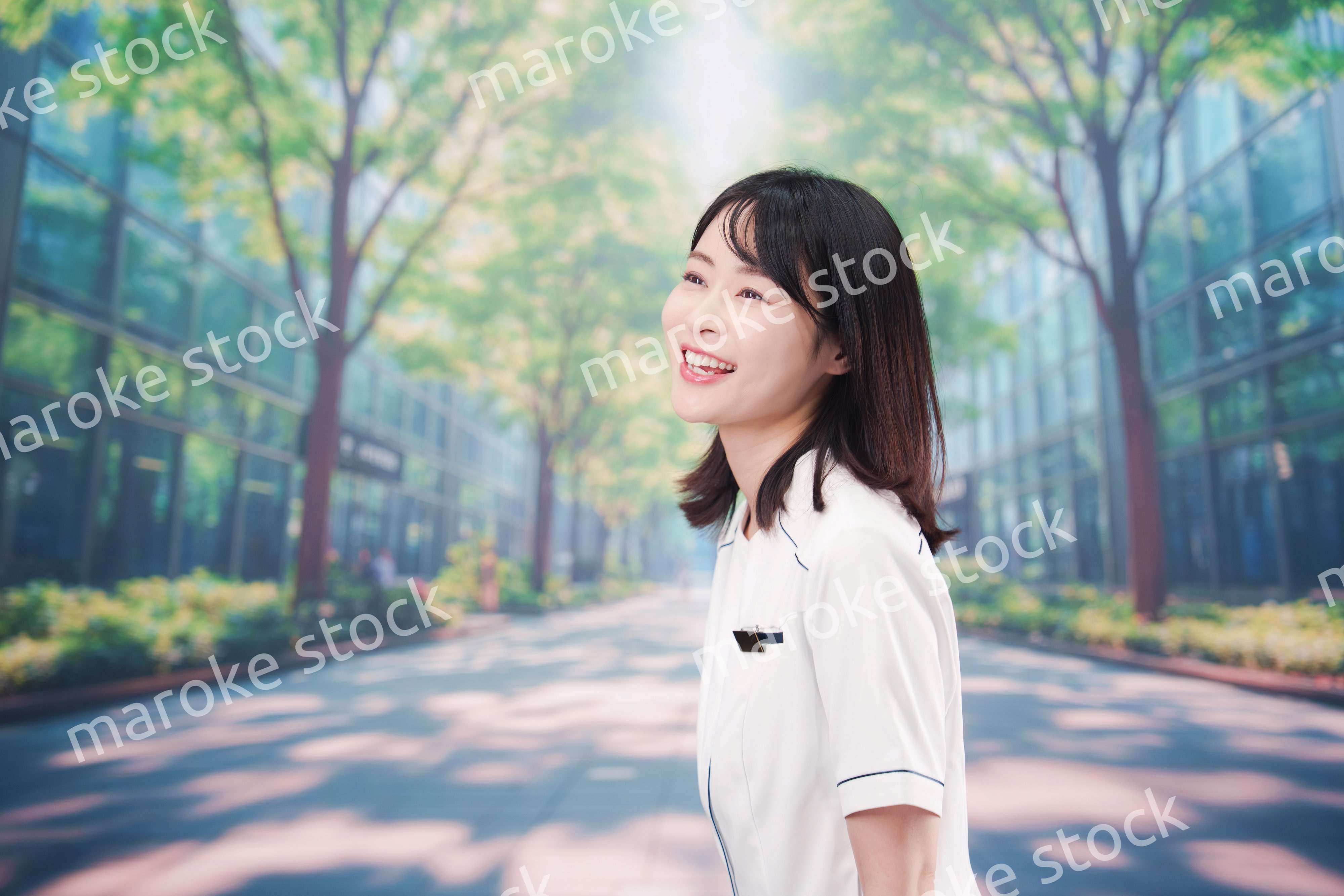 白衣を着て笑顔で外を歩く医療従事者の若い女性