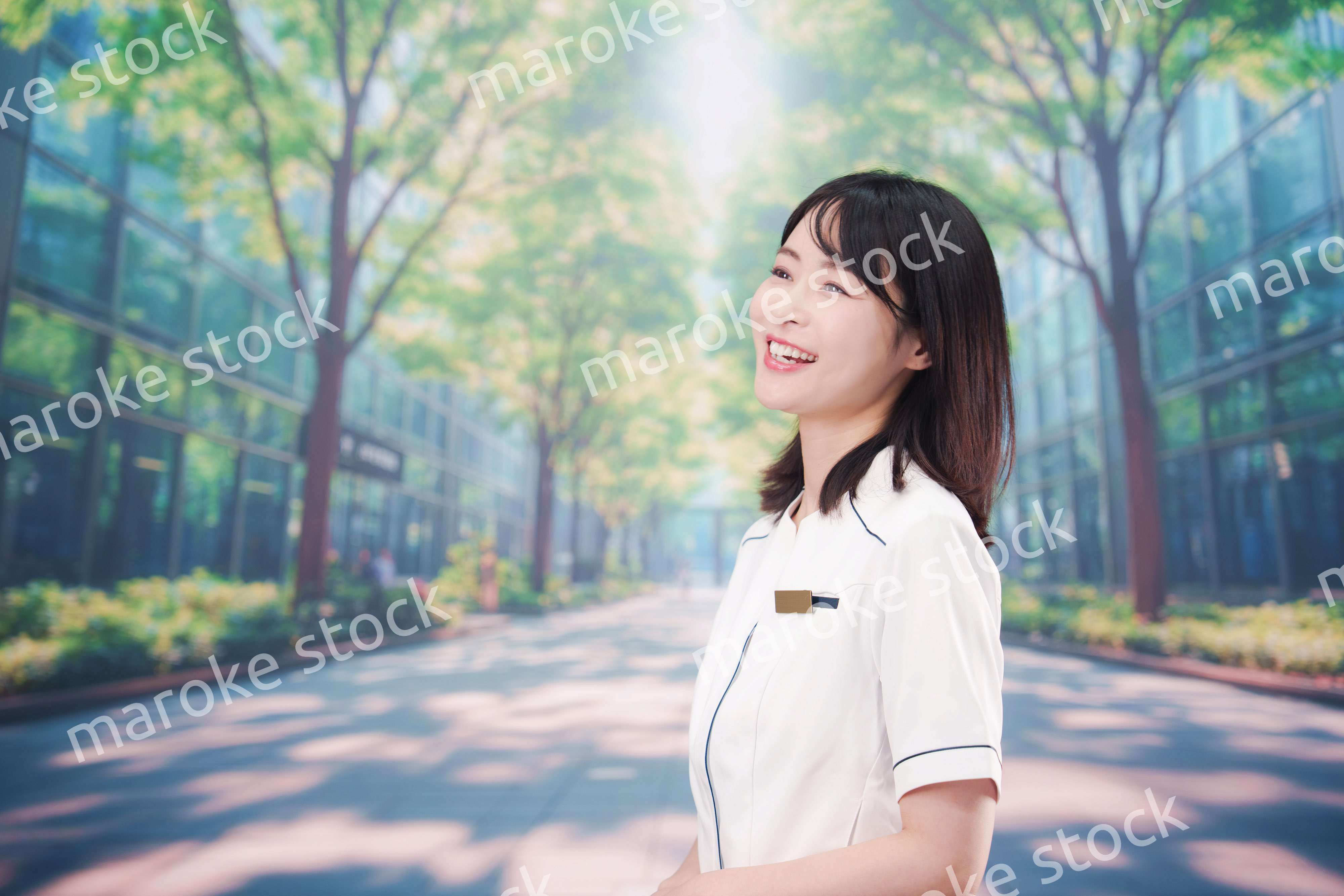 白衣を着て笑顔で外を歩く医療従事者の若い女性