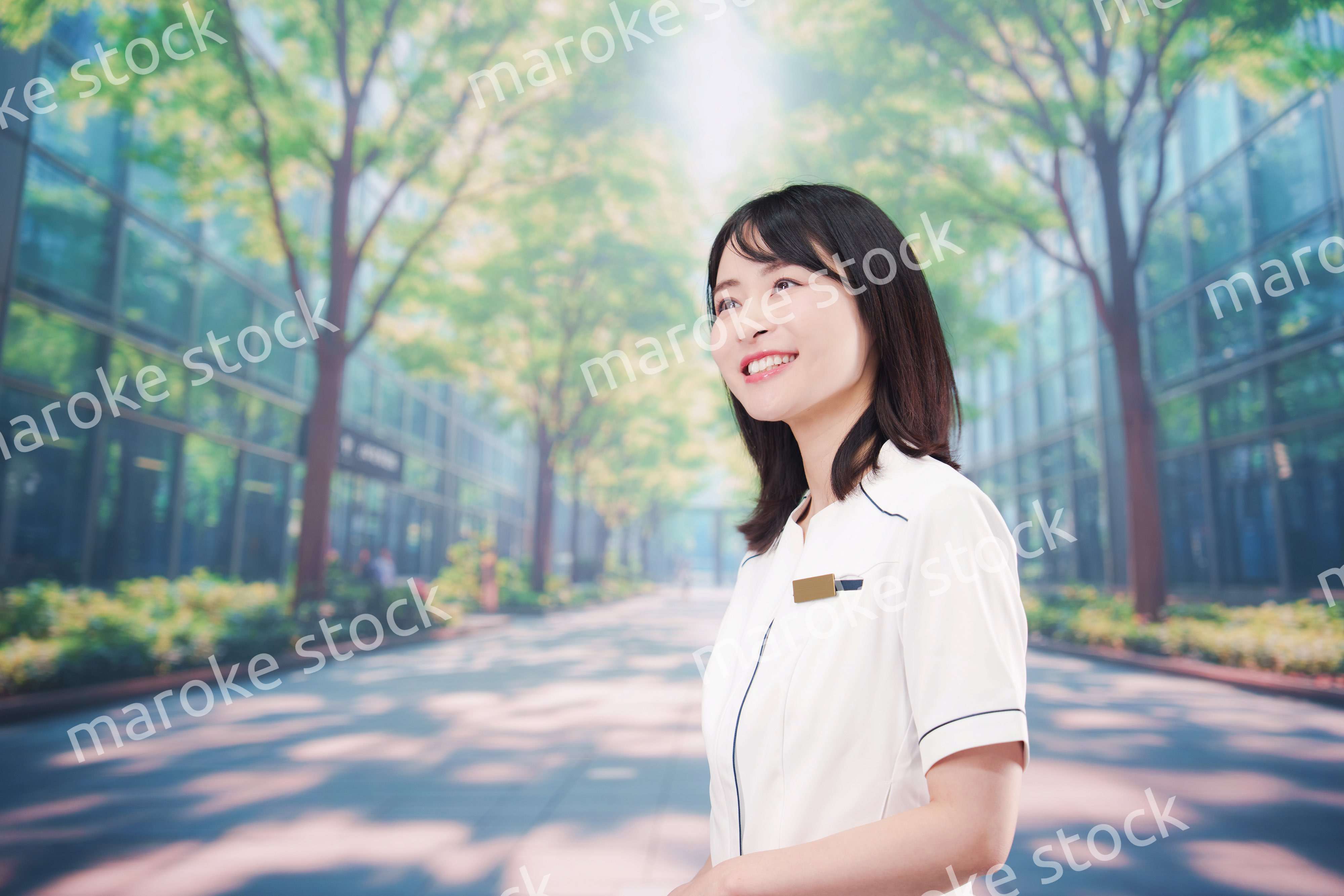 白衣を着て笑顔で外を歩く医療従事者の若い女性