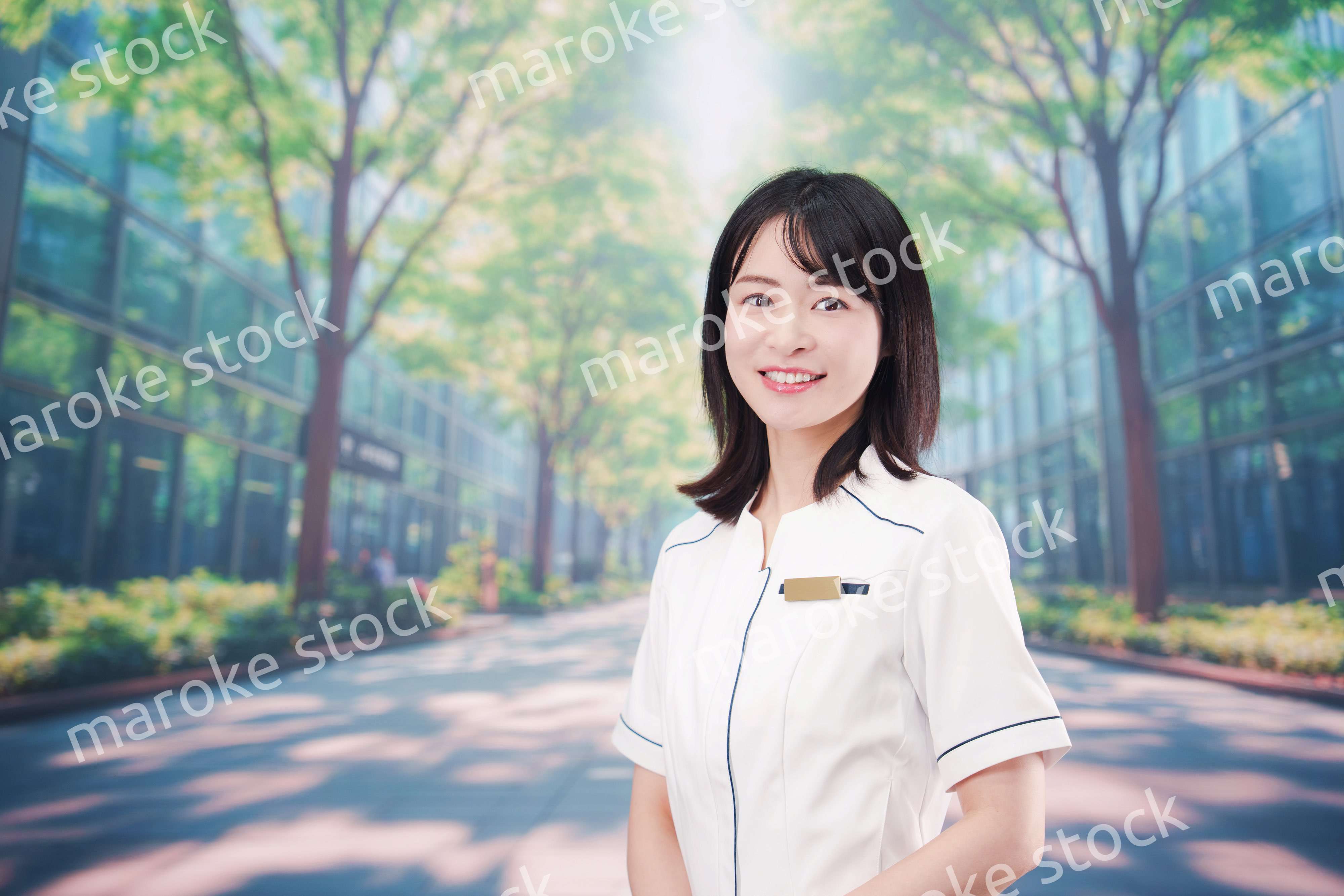 白衣を着て笑顔で外を歩く医療従事者の若い女性