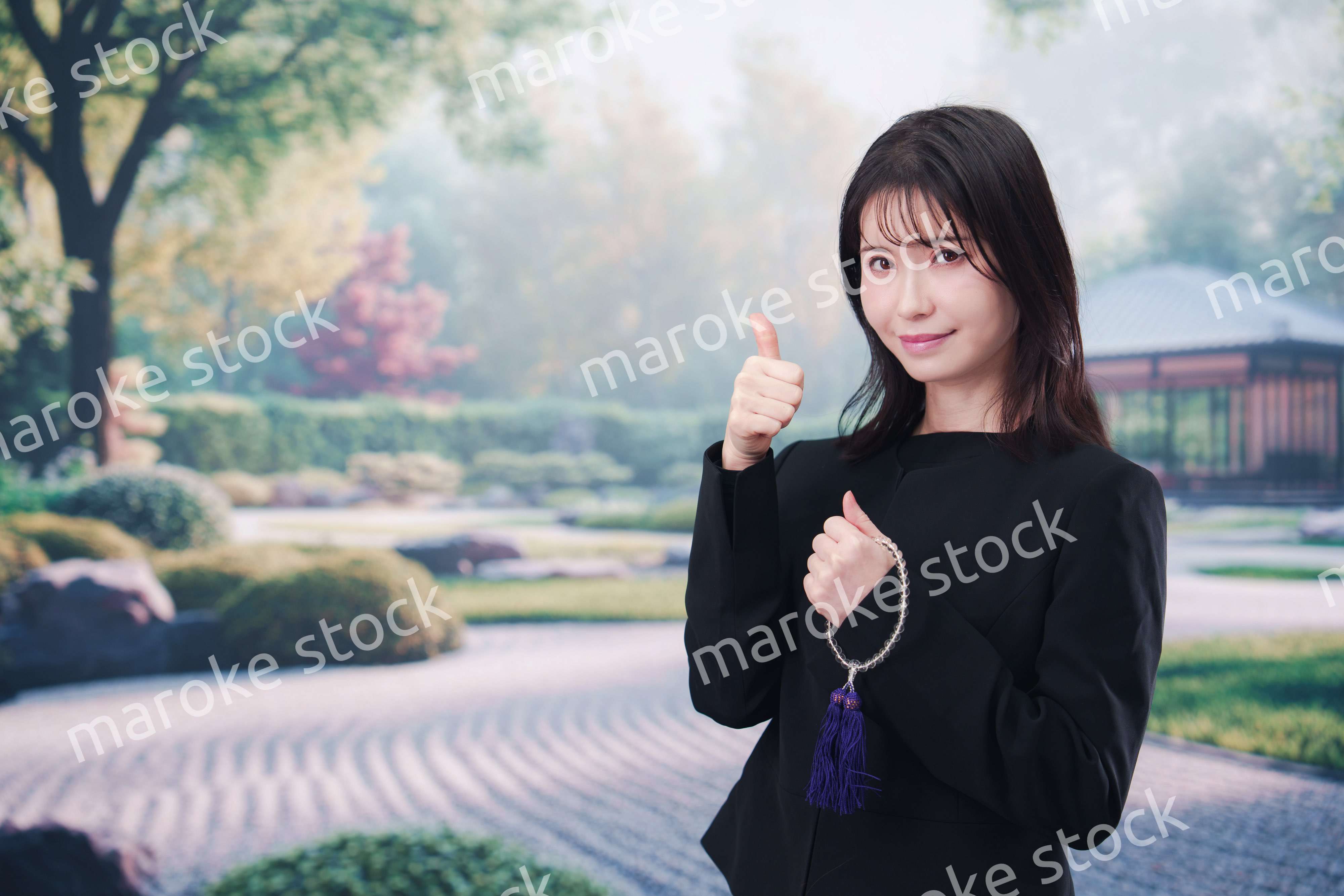 喪服を着て数珠を持って手を合わせる女性