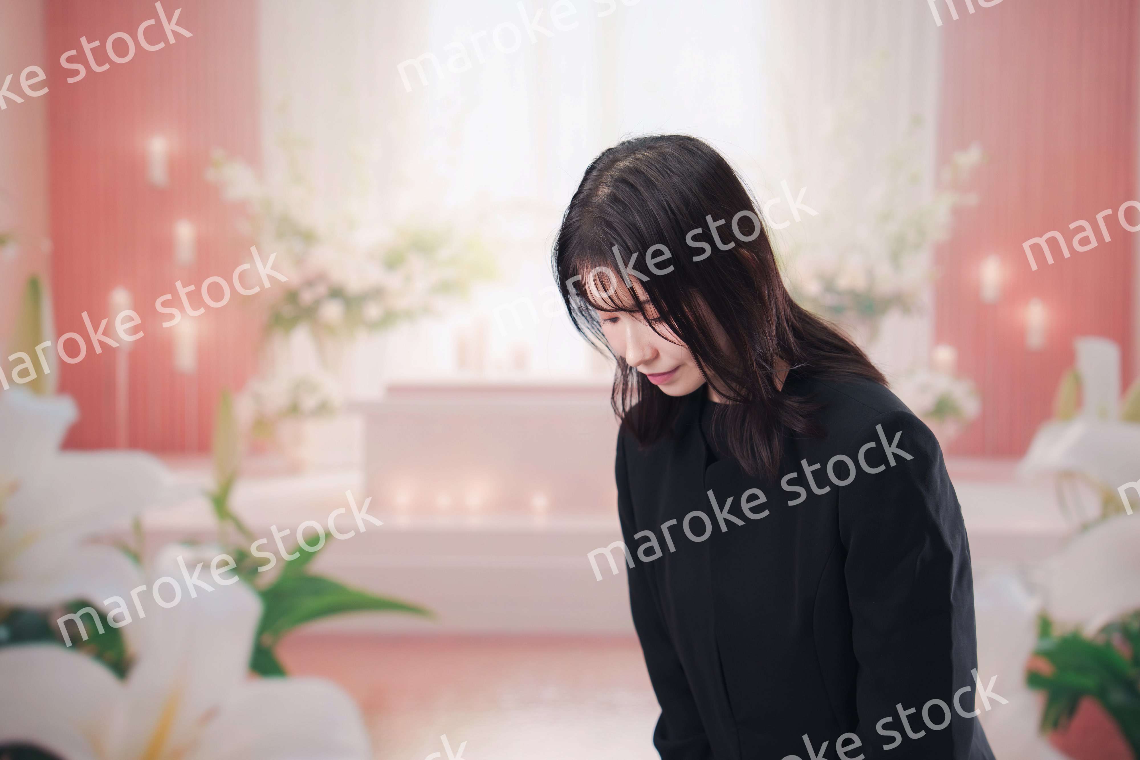 お葬式・お通夜で喪服を着て合掌をする若い女性