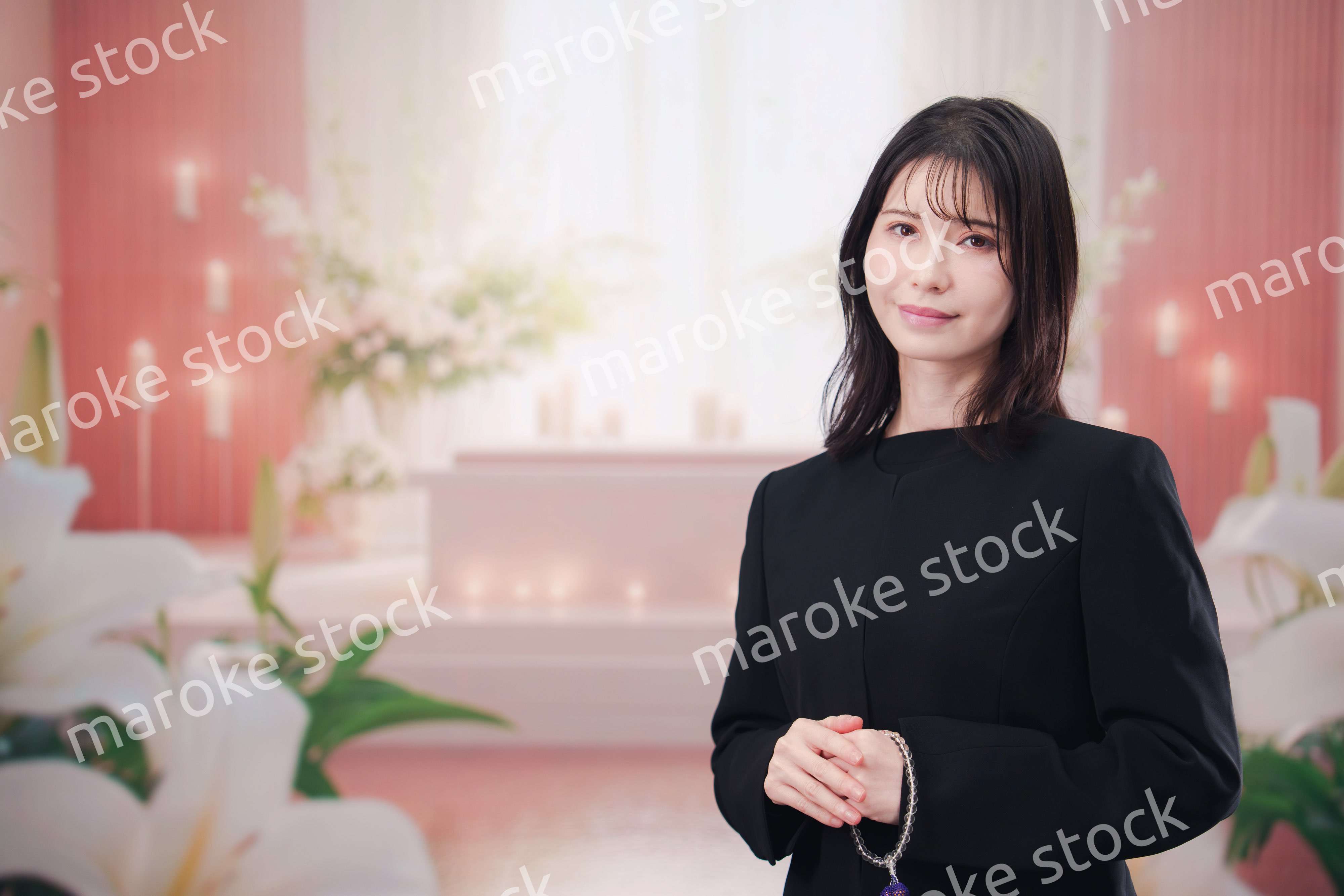 お葬式・お通夜で喪服を着て合掌をする若い女性