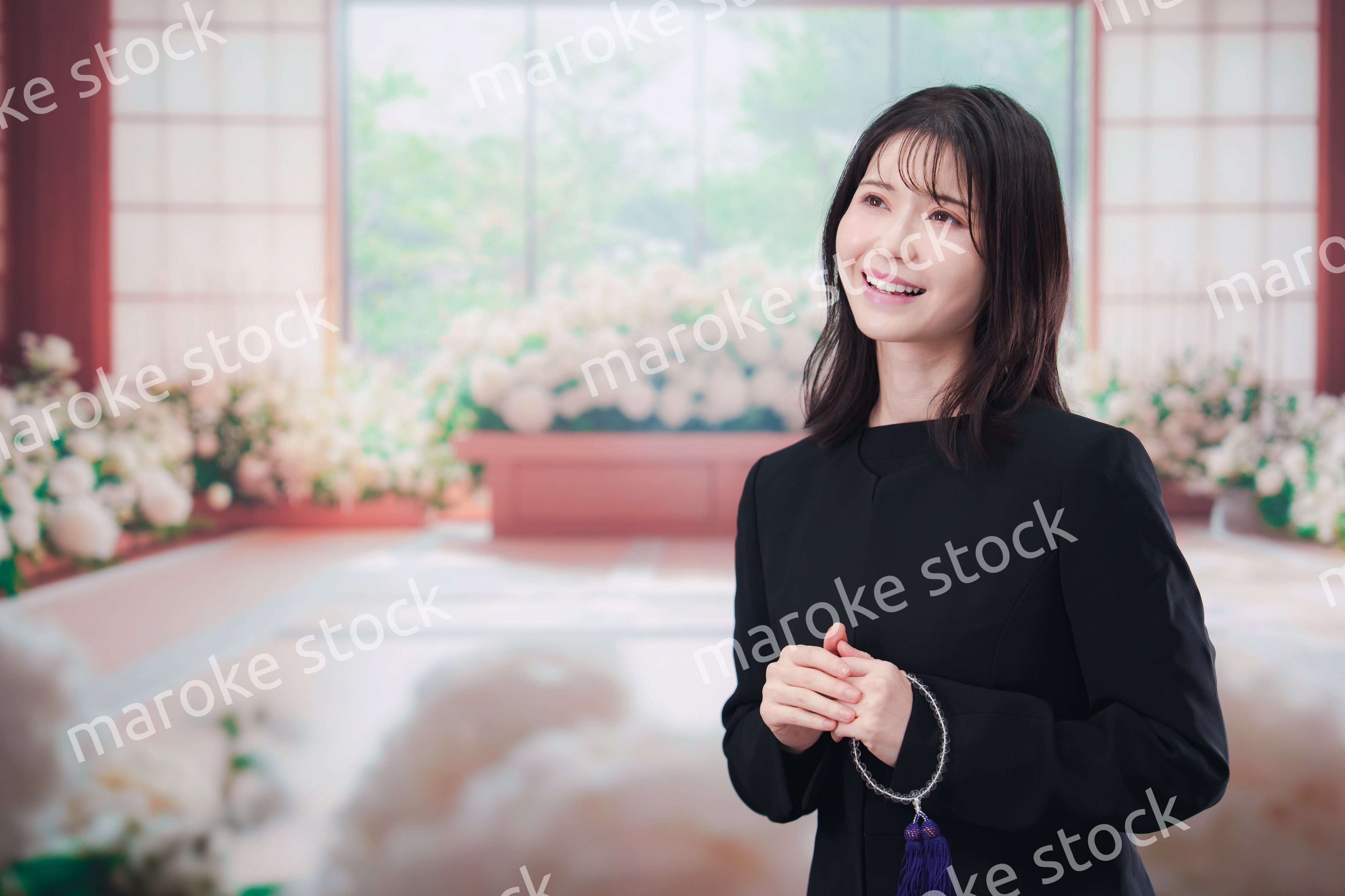 お葬式で喪服を着て数珠を持つ若い女性