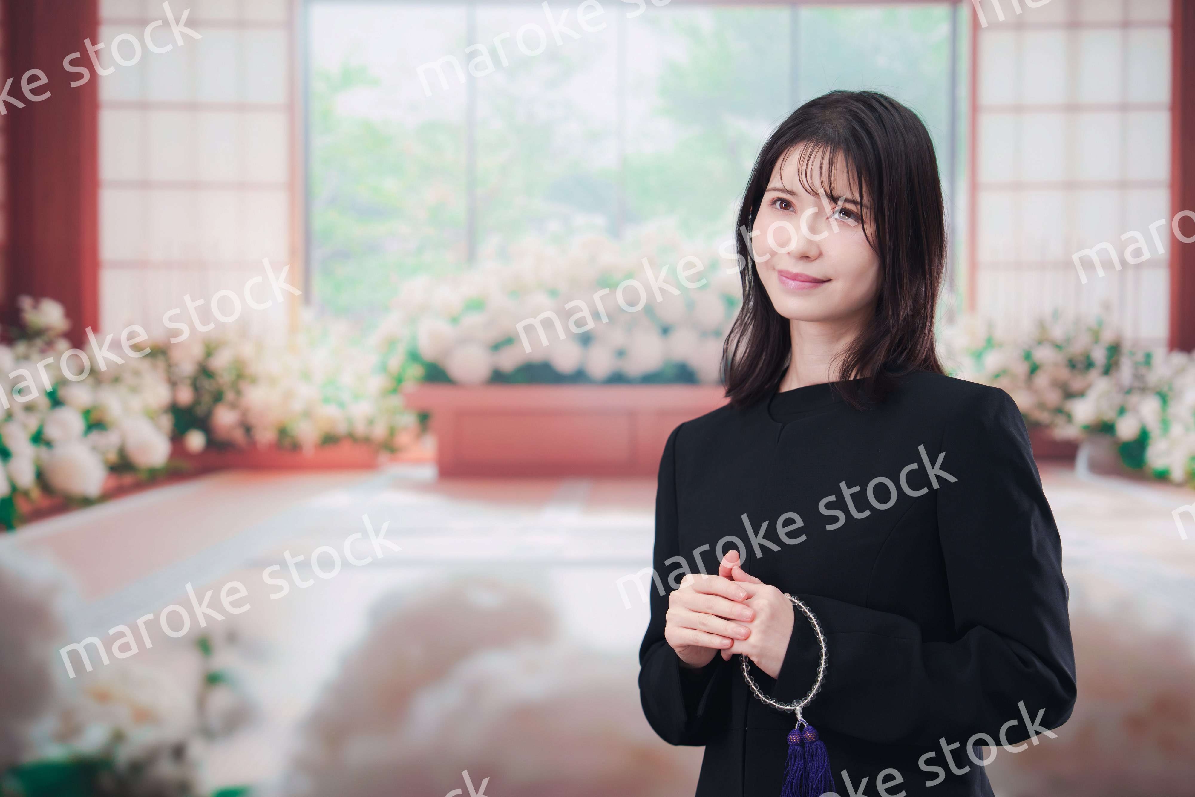 お葬式で喪服を着て数珠を持つ若い女性