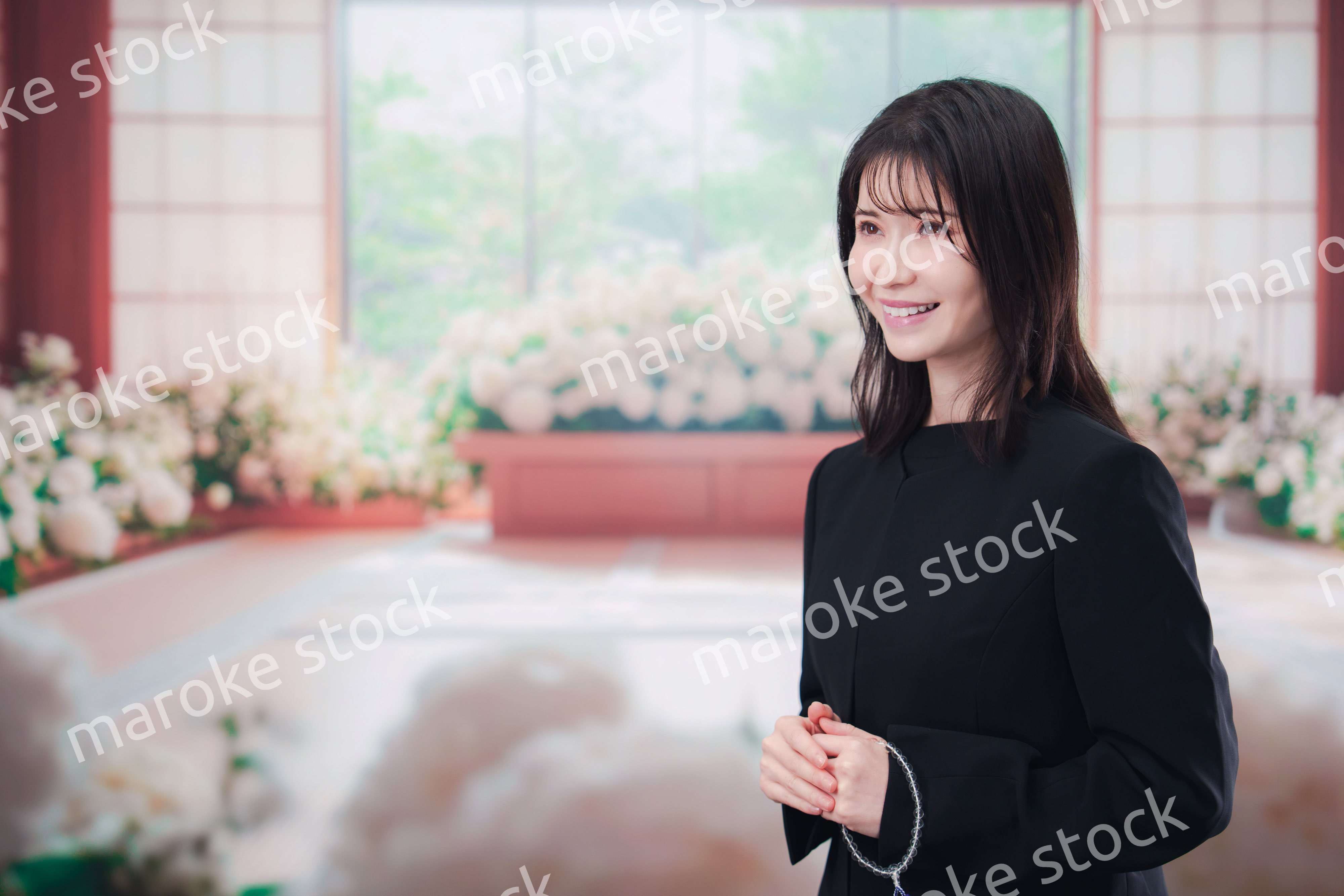 お葬式で喪服を着て数珠を持つ若い女性