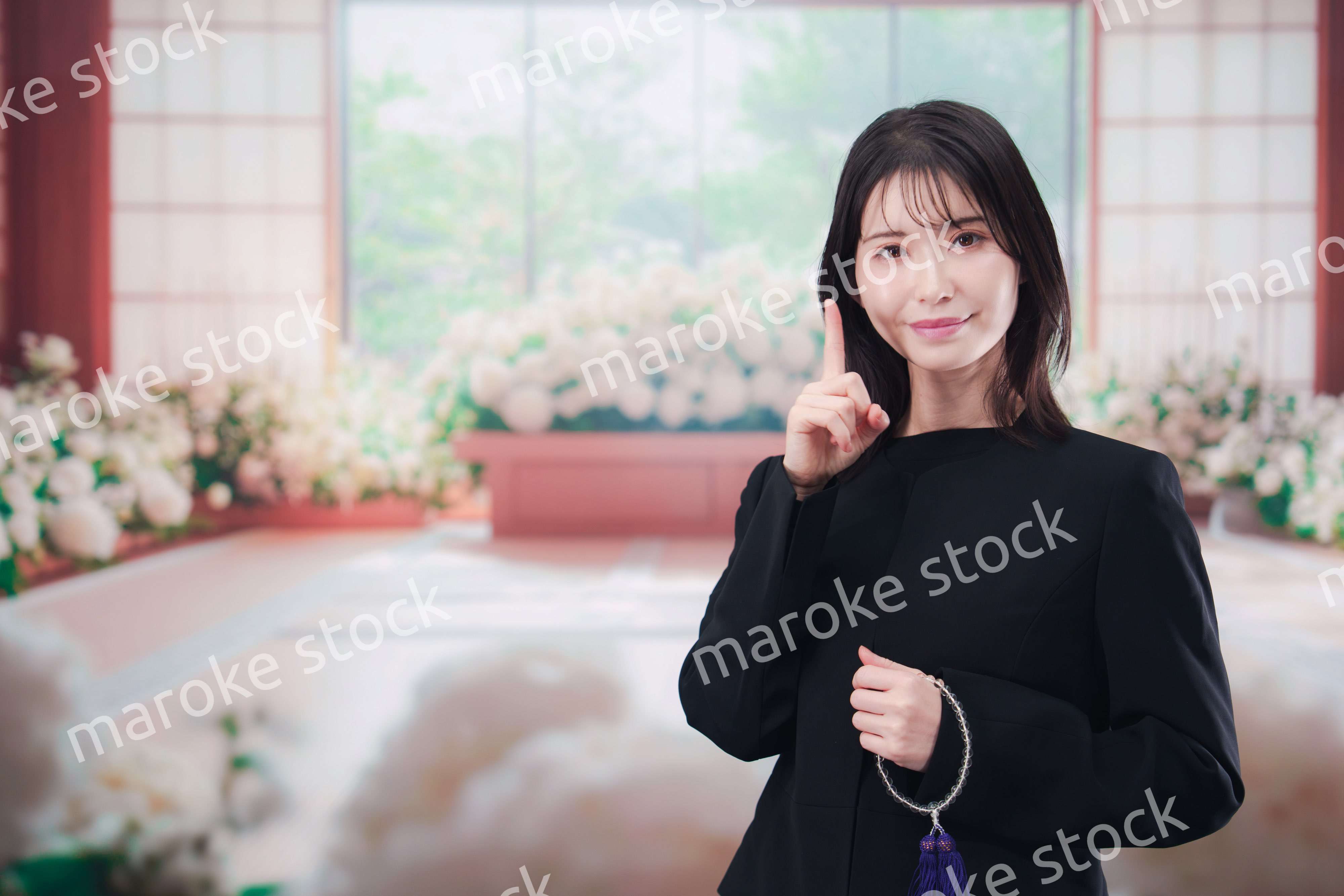 お葬式で喪服を着て数珠を持つ若い女性