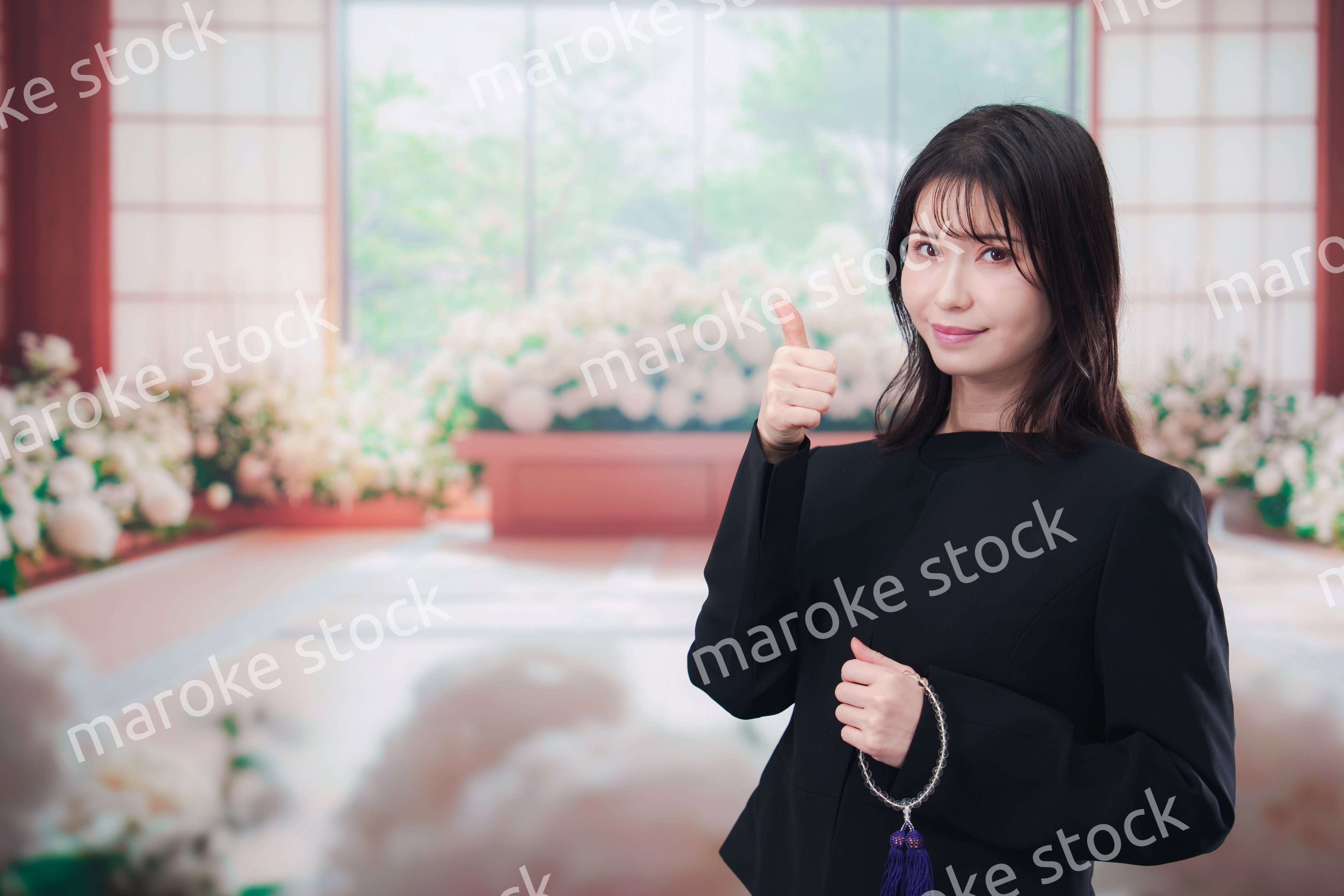 お葬式で喪服を着て数珠を持つ若い女性