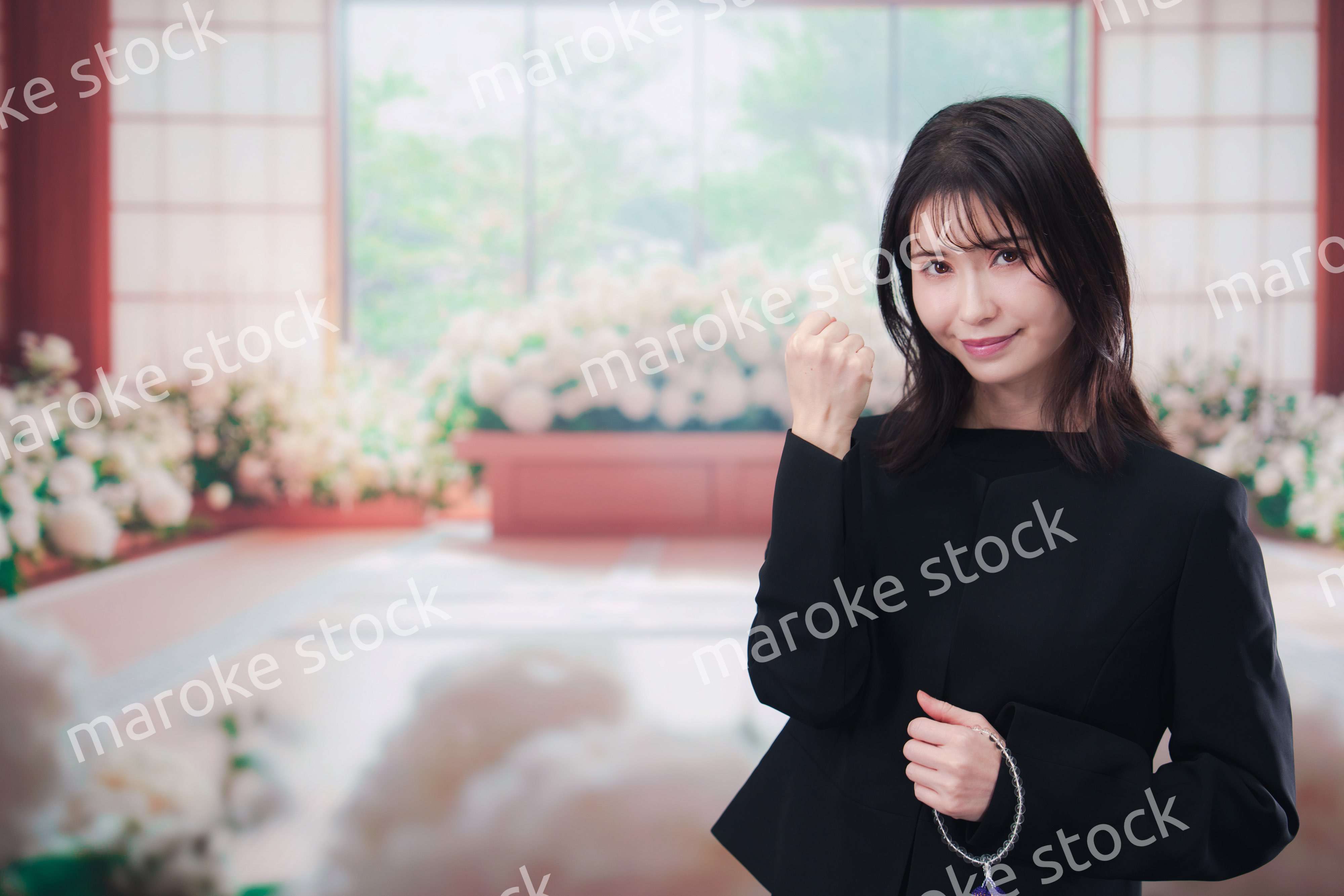 お葬式で喪服を着て数珠を持つ若い女性