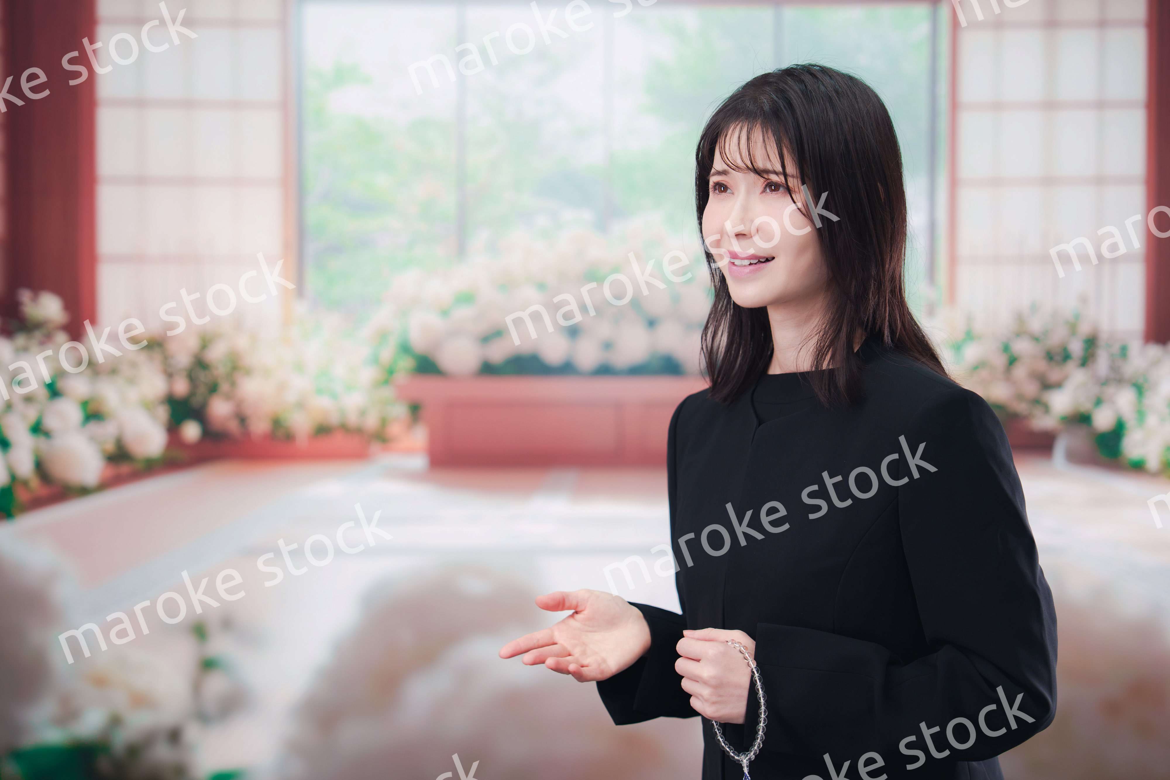お葬式で喪服を着て数珠を持つ若い女性