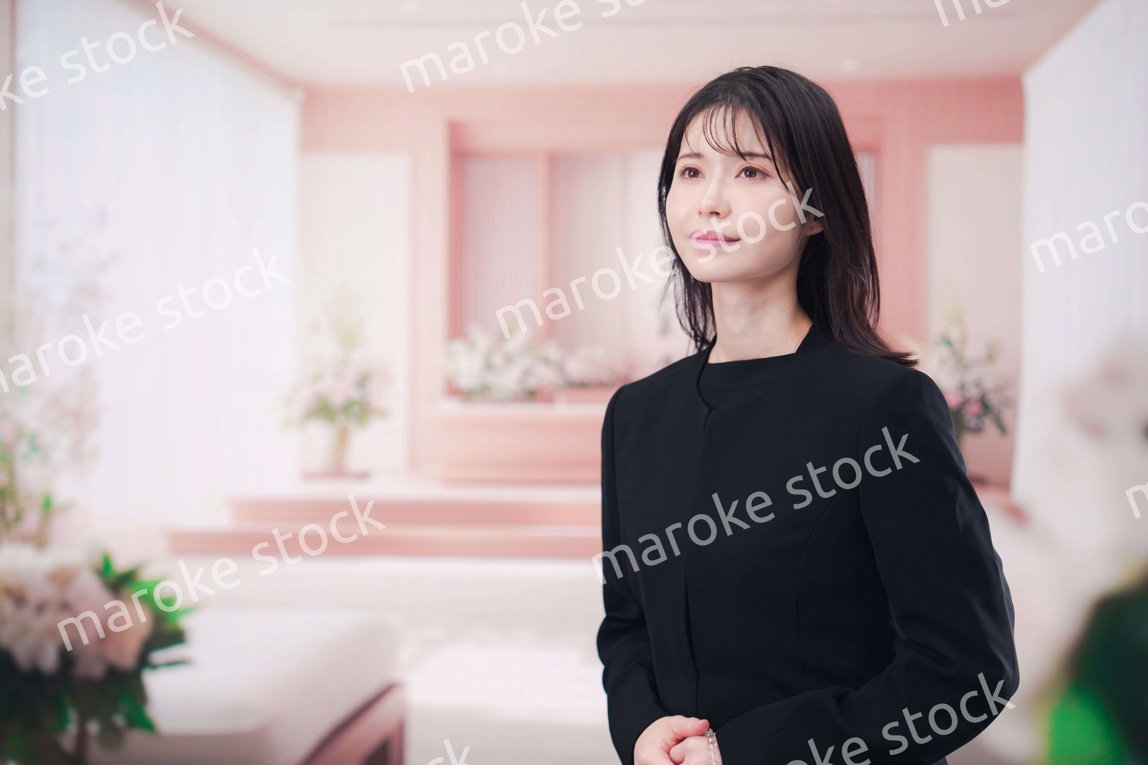 お葬式で喪服を着て数珠を持つ若い女性