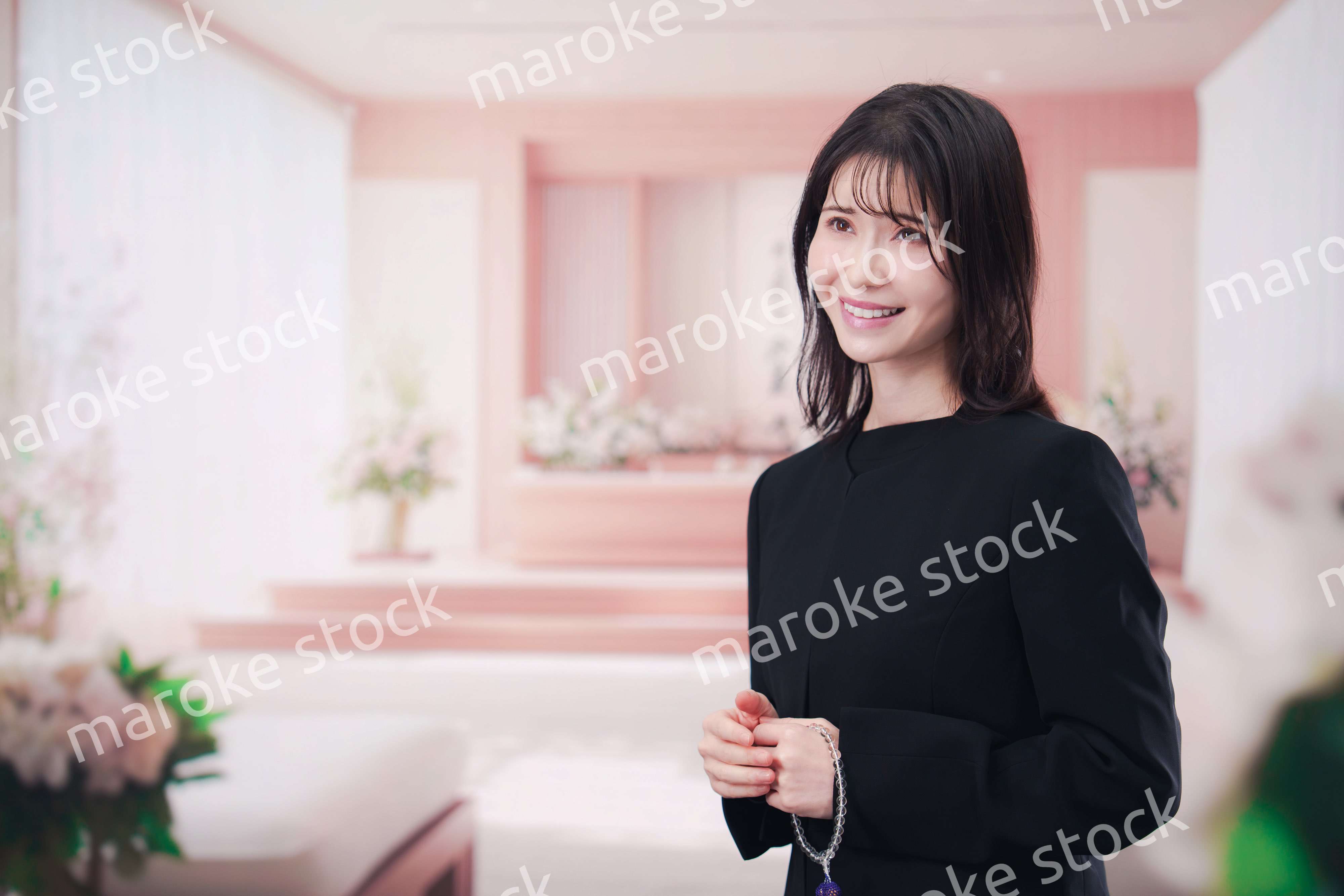 お葬式で喪服を着て数珠を持つ若い女性