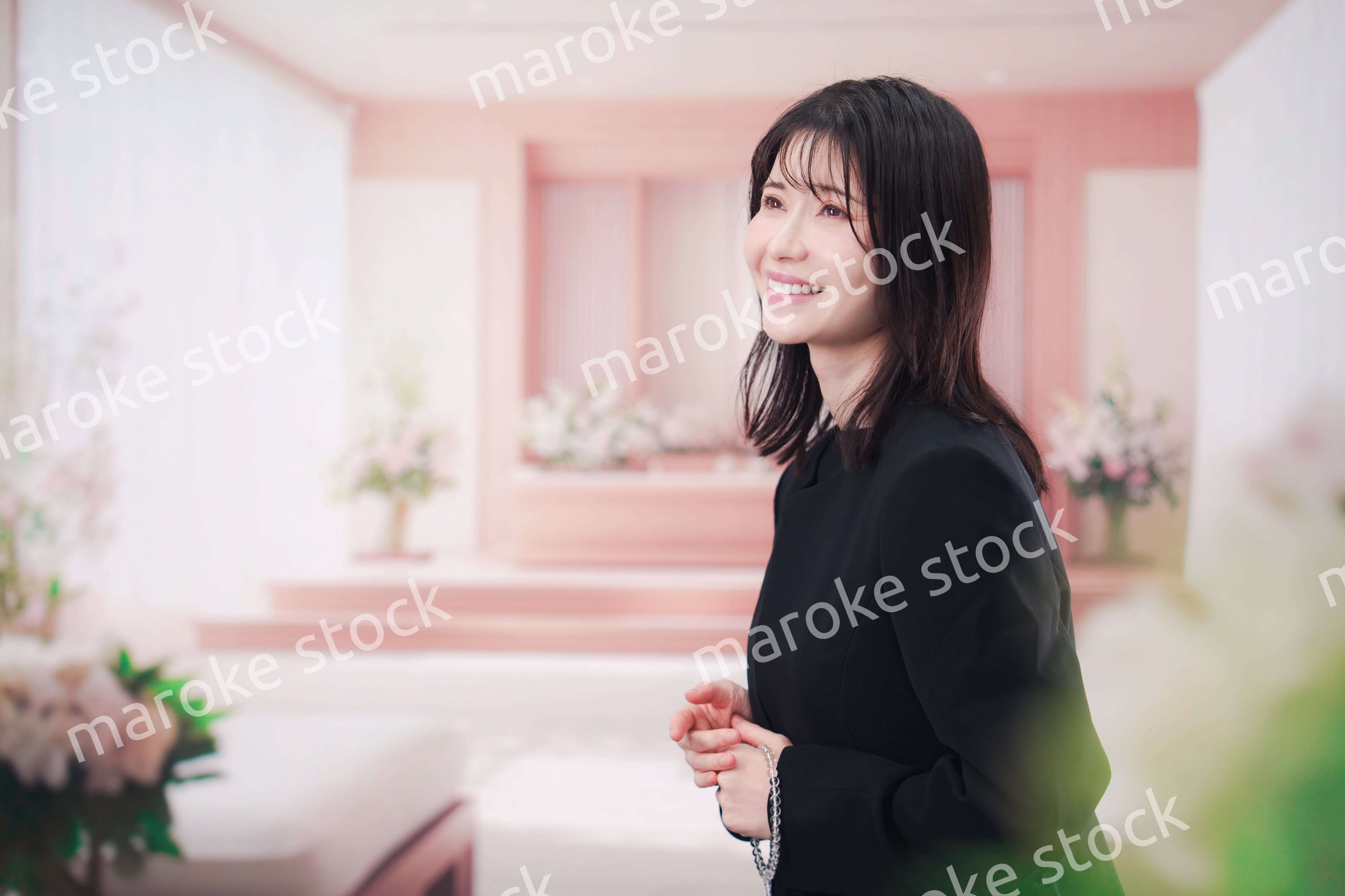 お葬式で喪服を着て数珠を持つ若い女性