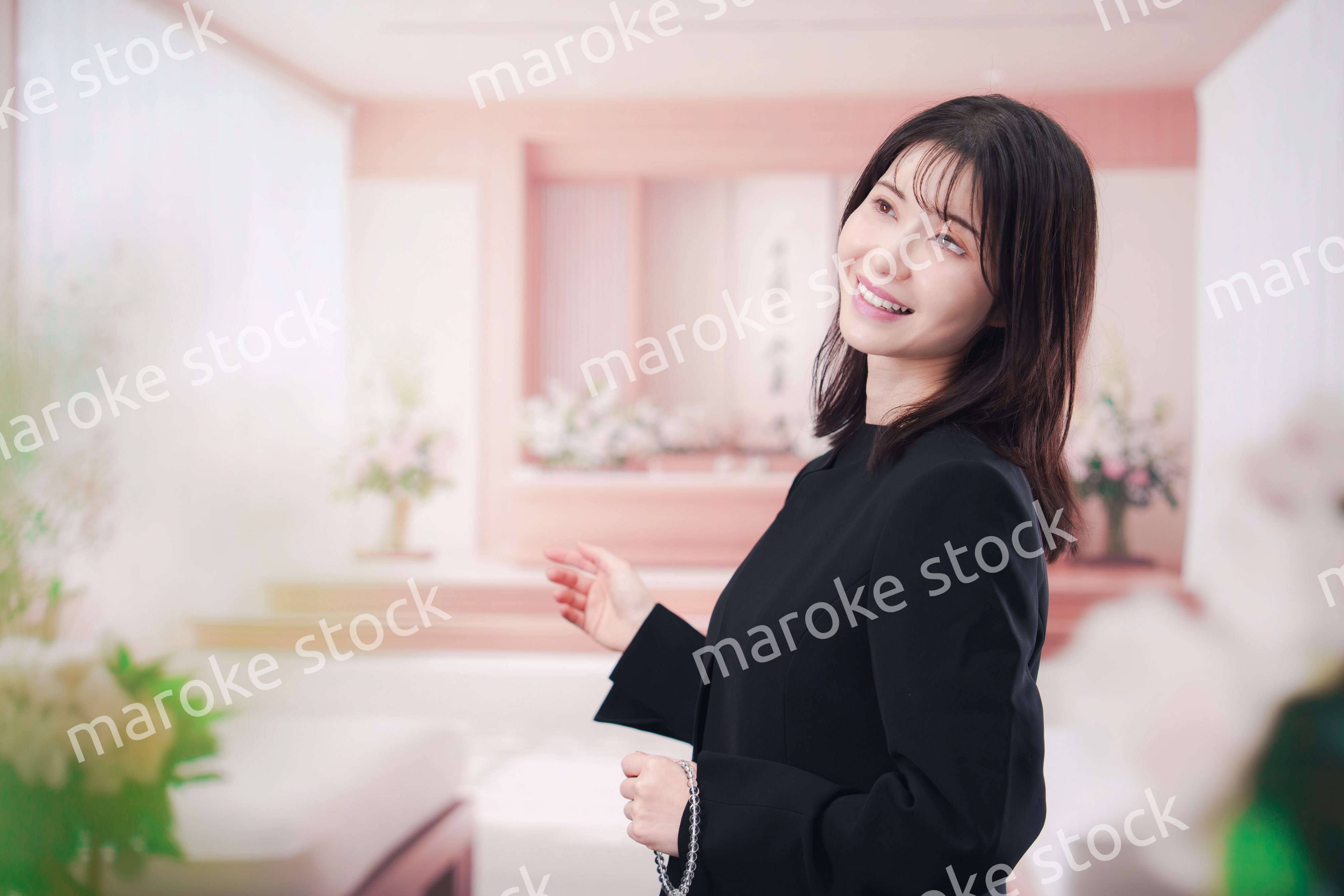 お葬式で喪服を着て数珠を持つ若い女性