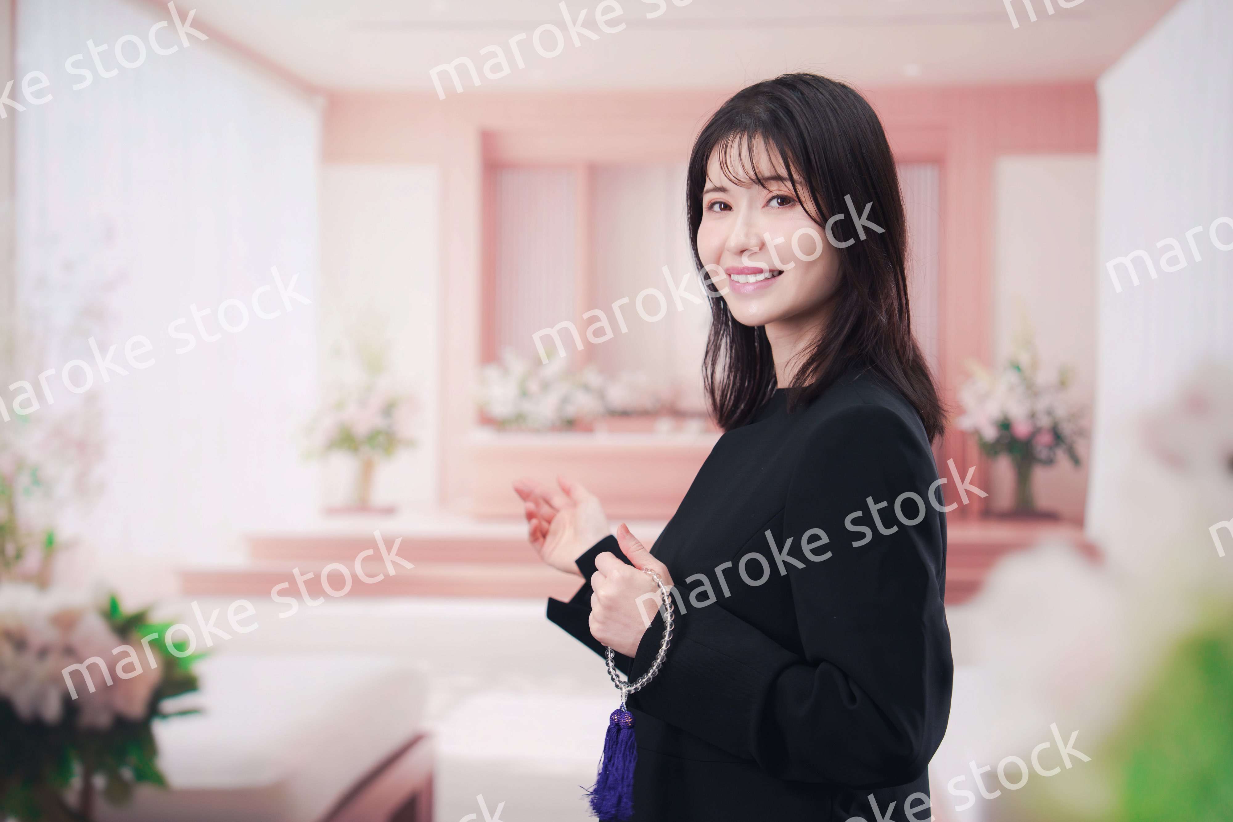 お葬式で喪服を着て数珠を持つ若い女性
