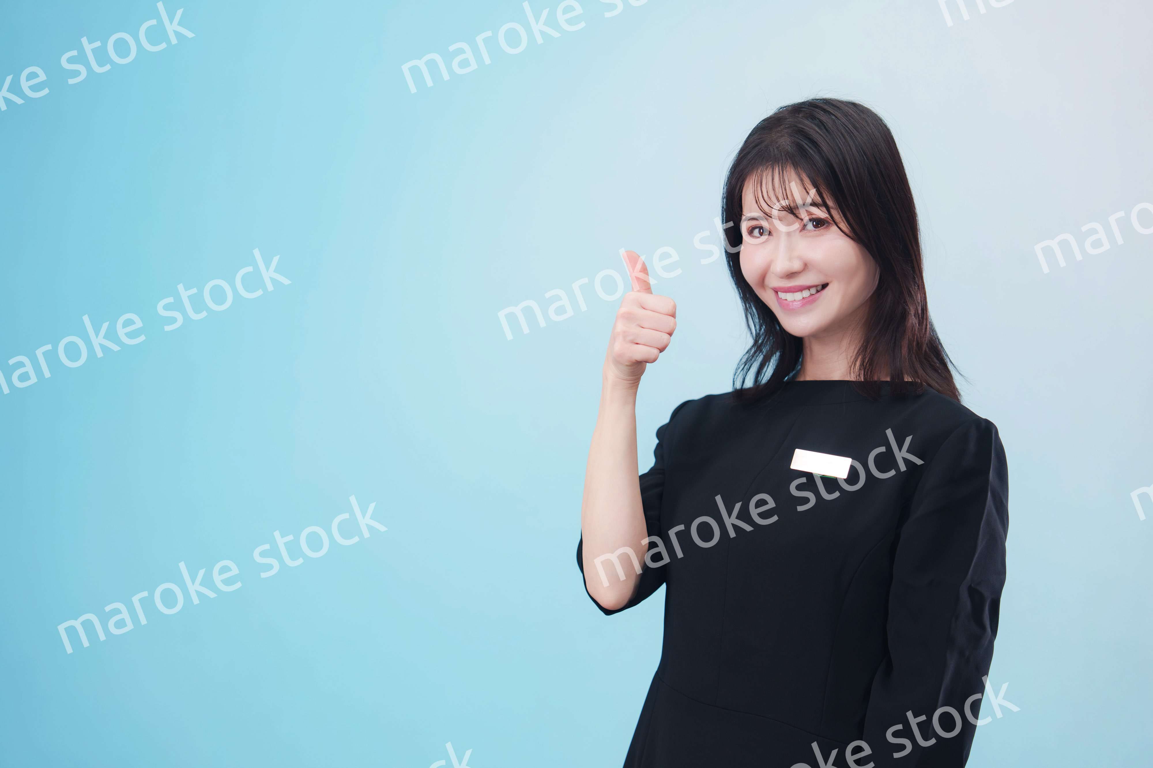 黒い服に名札をつけた笑顔のスタッフ（水色背景）