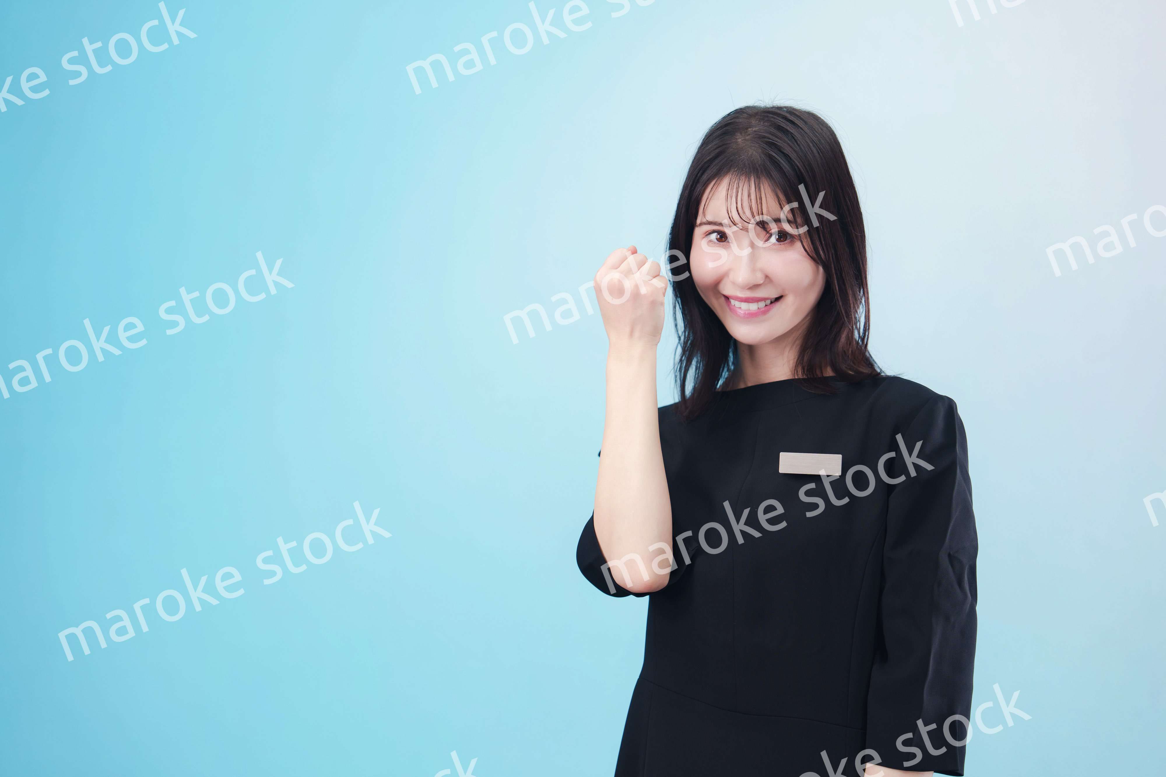 黒い服に名札をつけた笑顔のスタッフ（水色背景）