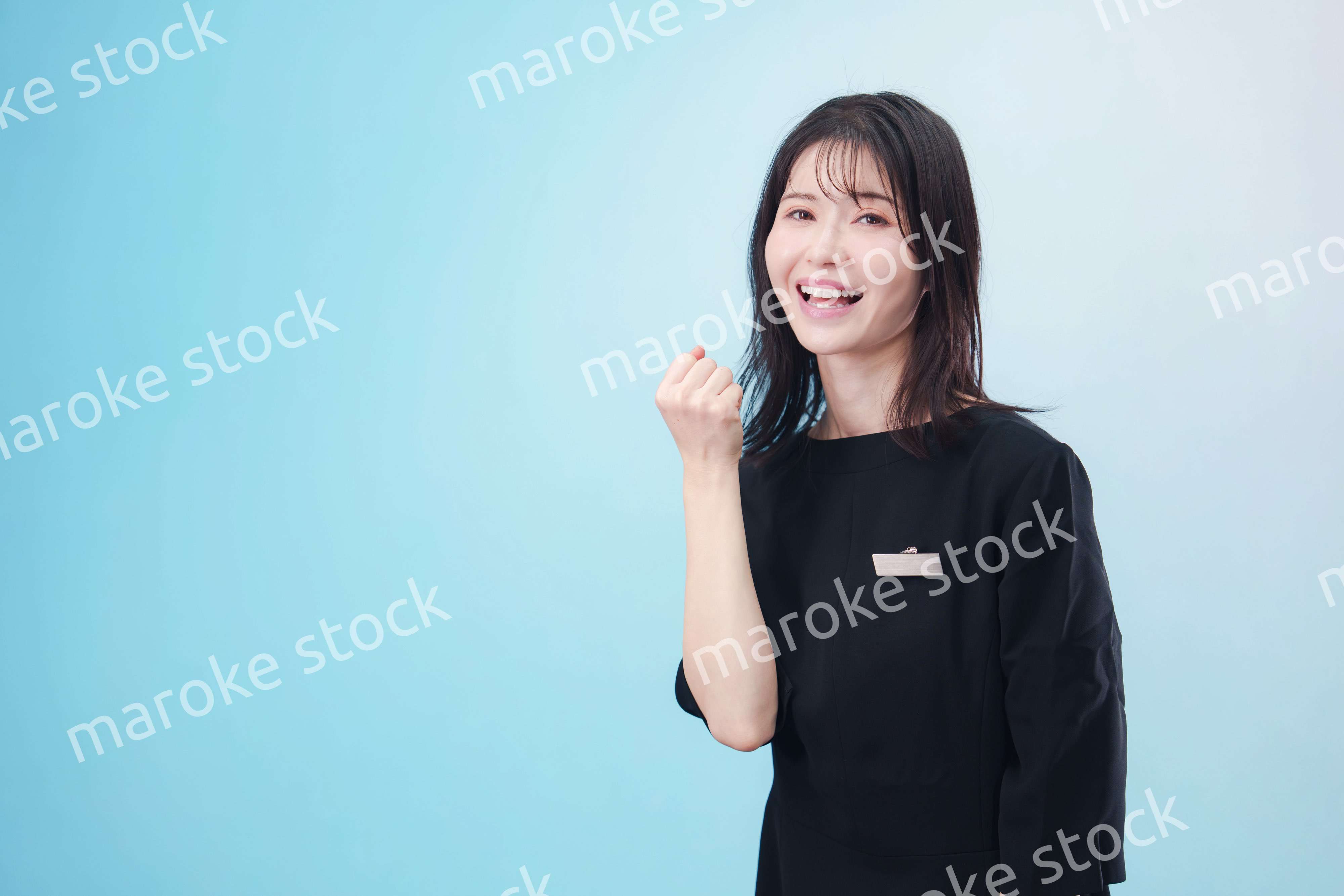 黒い服に名札をつけた笑顔のスタッフ（水色背景）