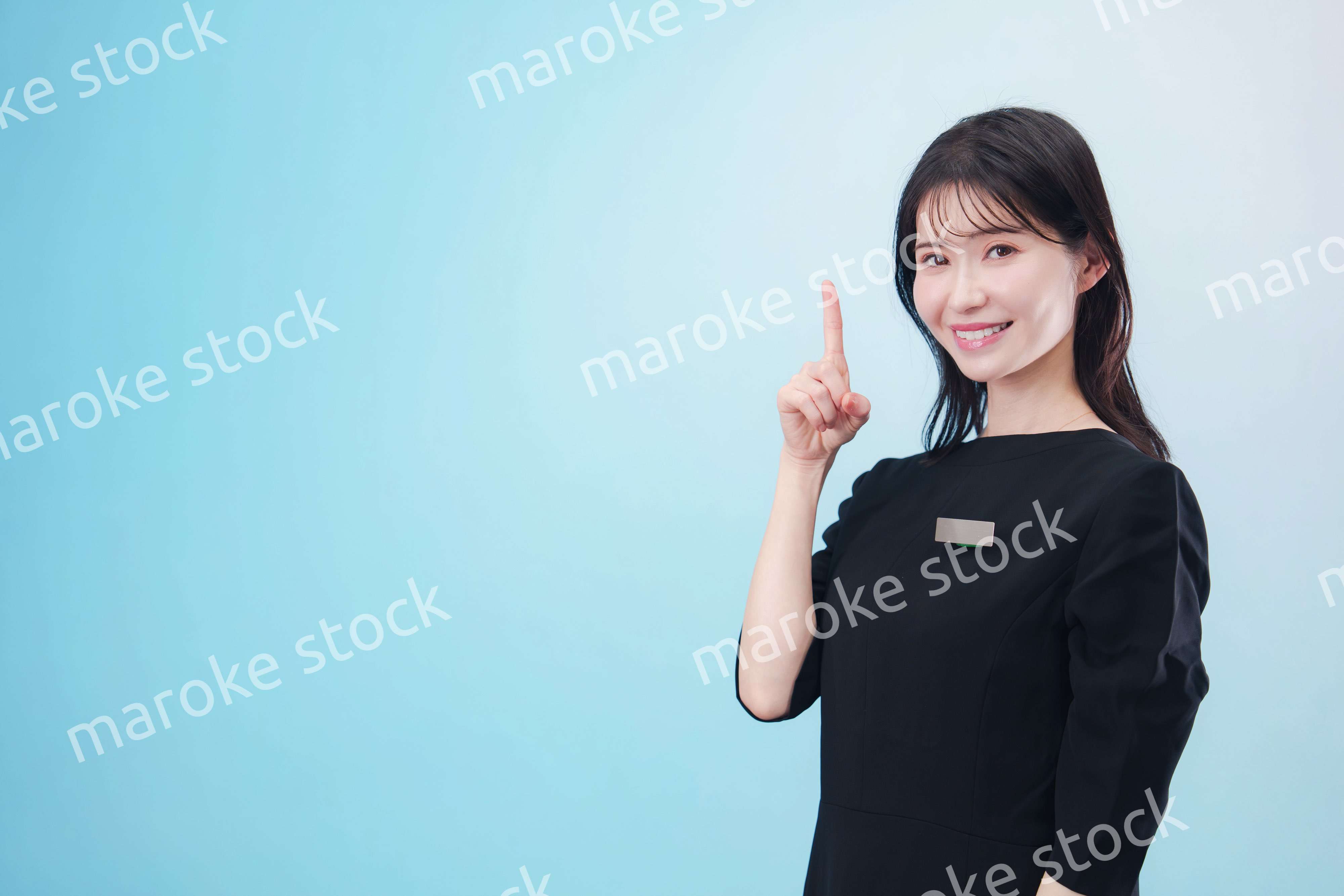 黒い服に名札をつけた笑顔のスタッフ（水色背景）