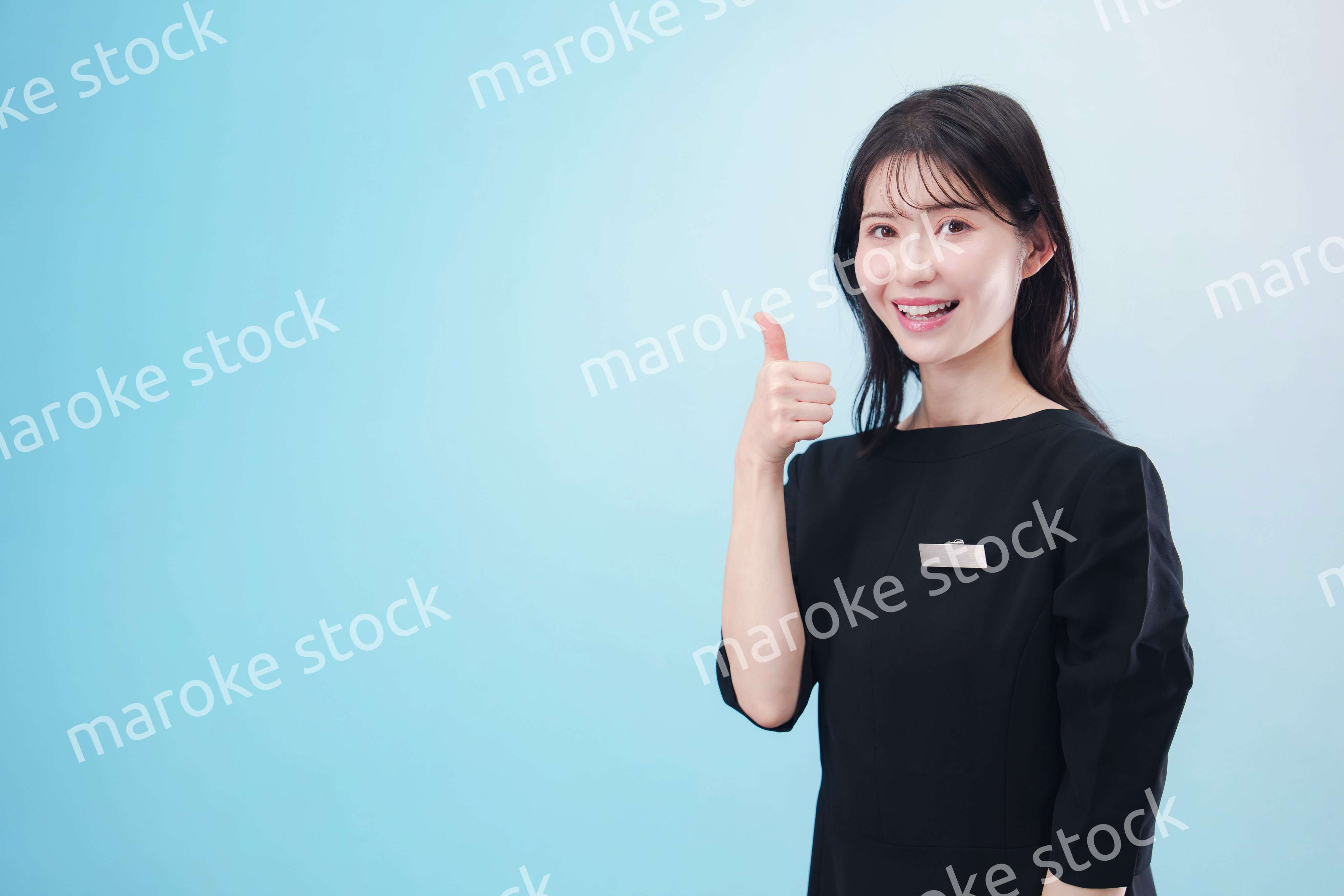 黒い服に名札をつけた笑顔のスタッフ（水色背景）