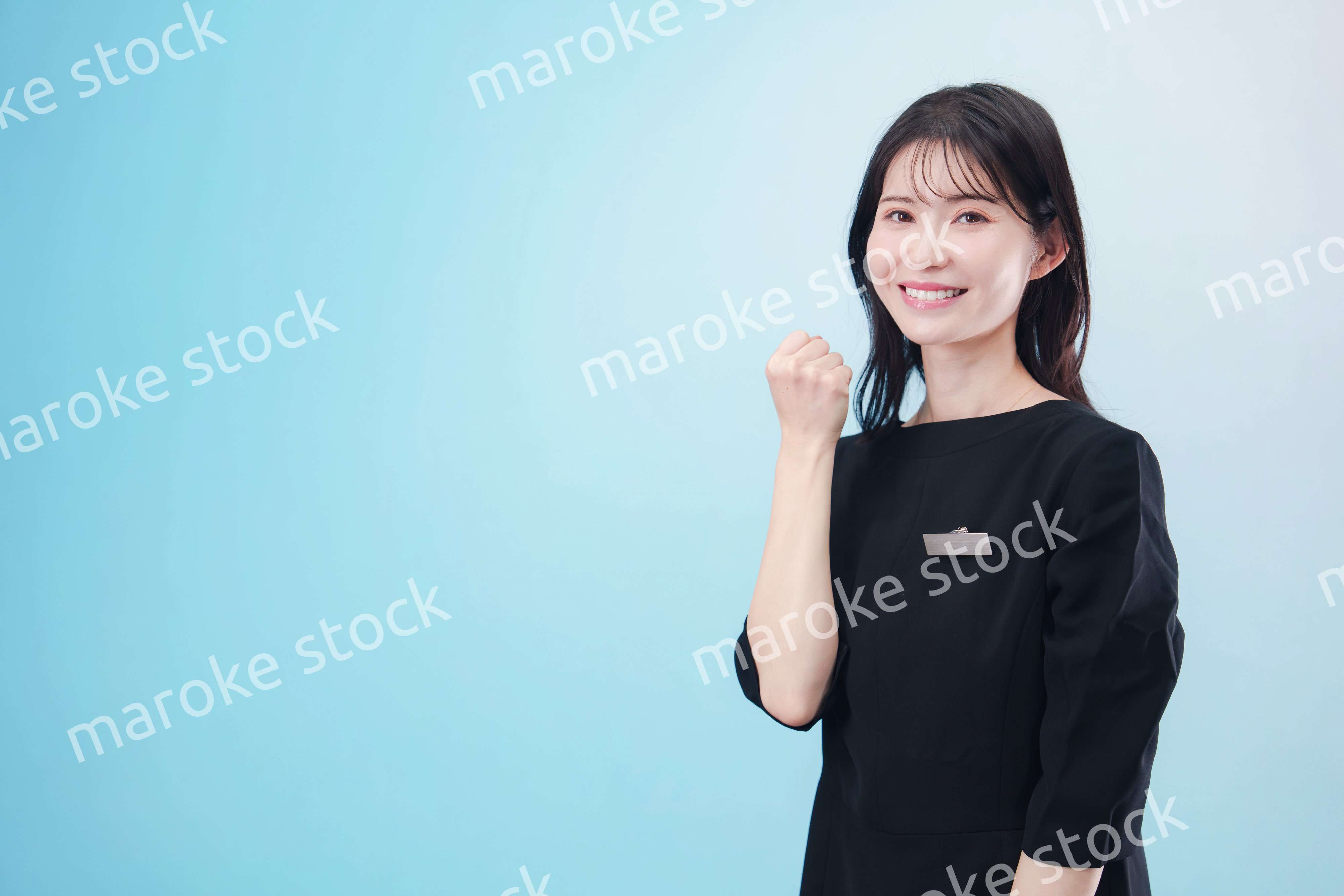 黒い服に名札をつけた笑顔のスタッフ（水色背景）