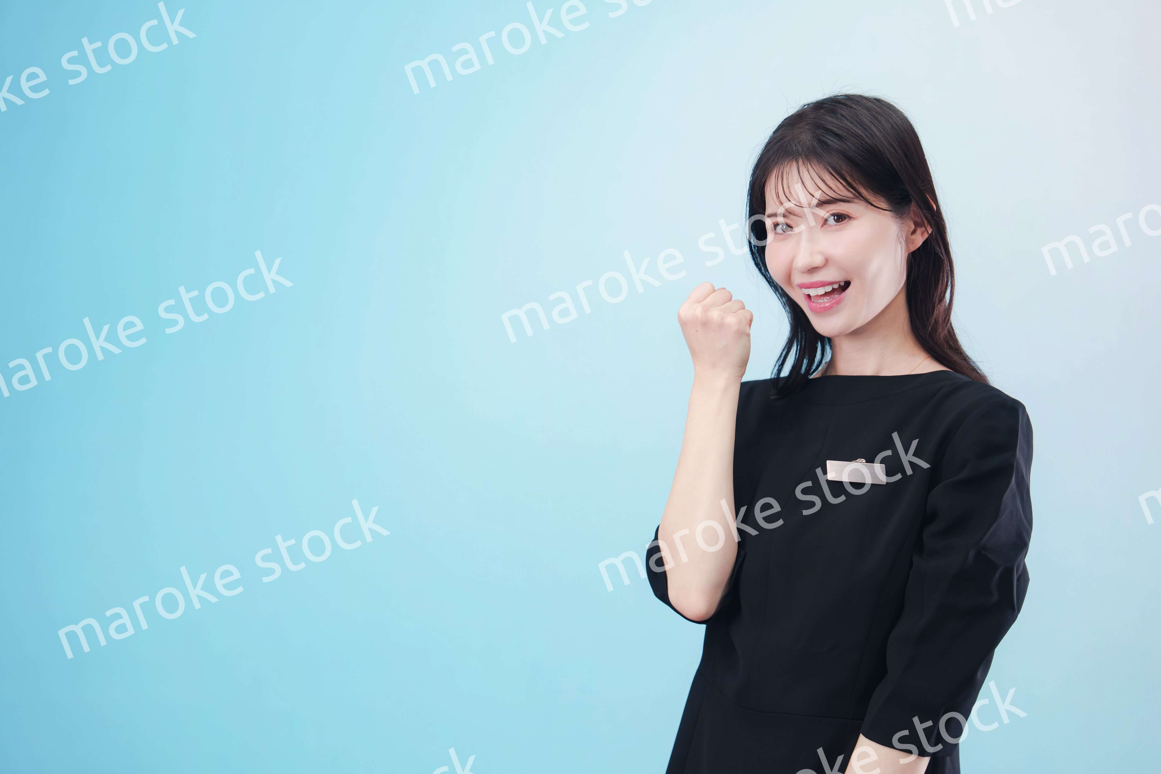 黒い服に名札をつけた笑顔のスタッフ（水色背景）