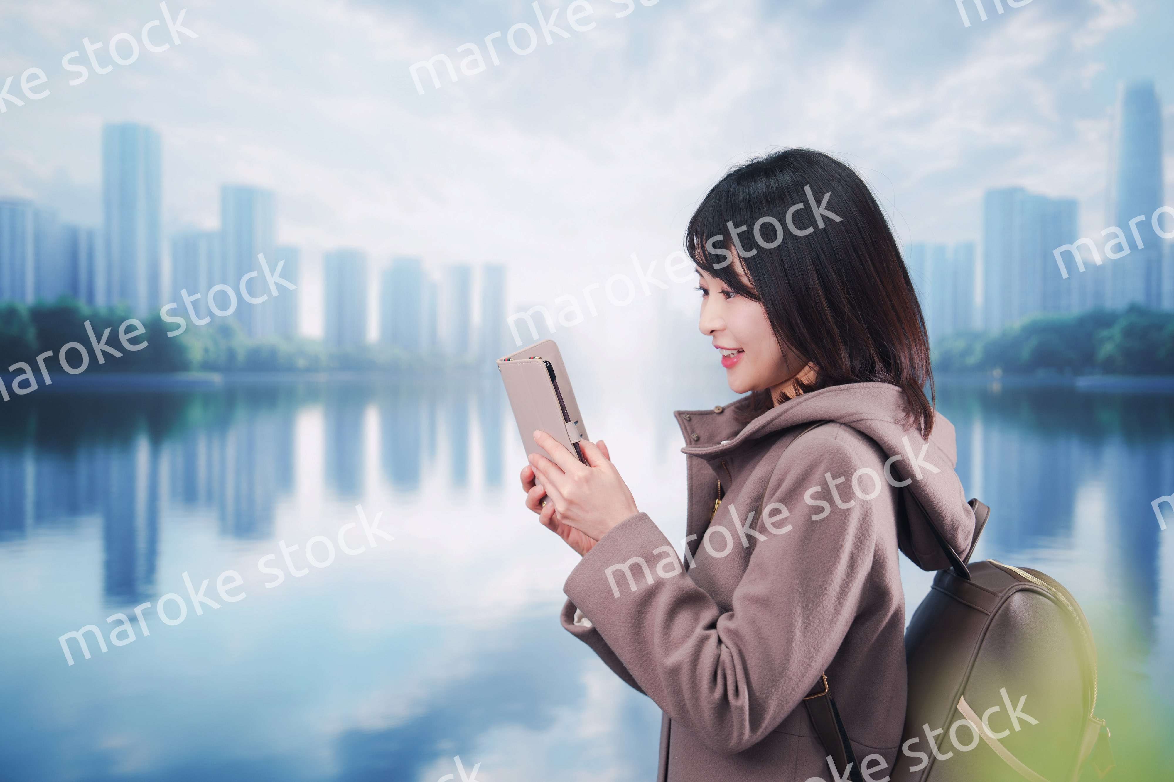 コートを着てスマホを使いながら外を歩く若い女性