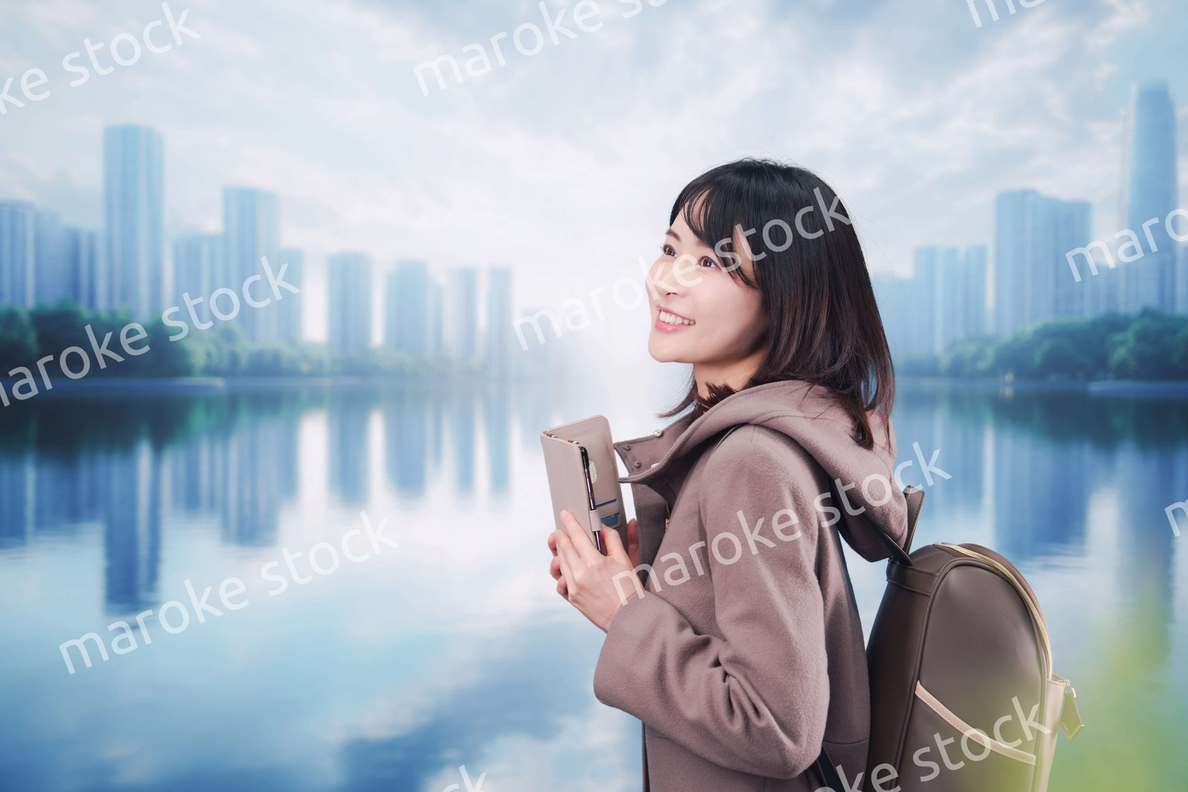 コートを着てスマホを使いながら外を歩く若い女性