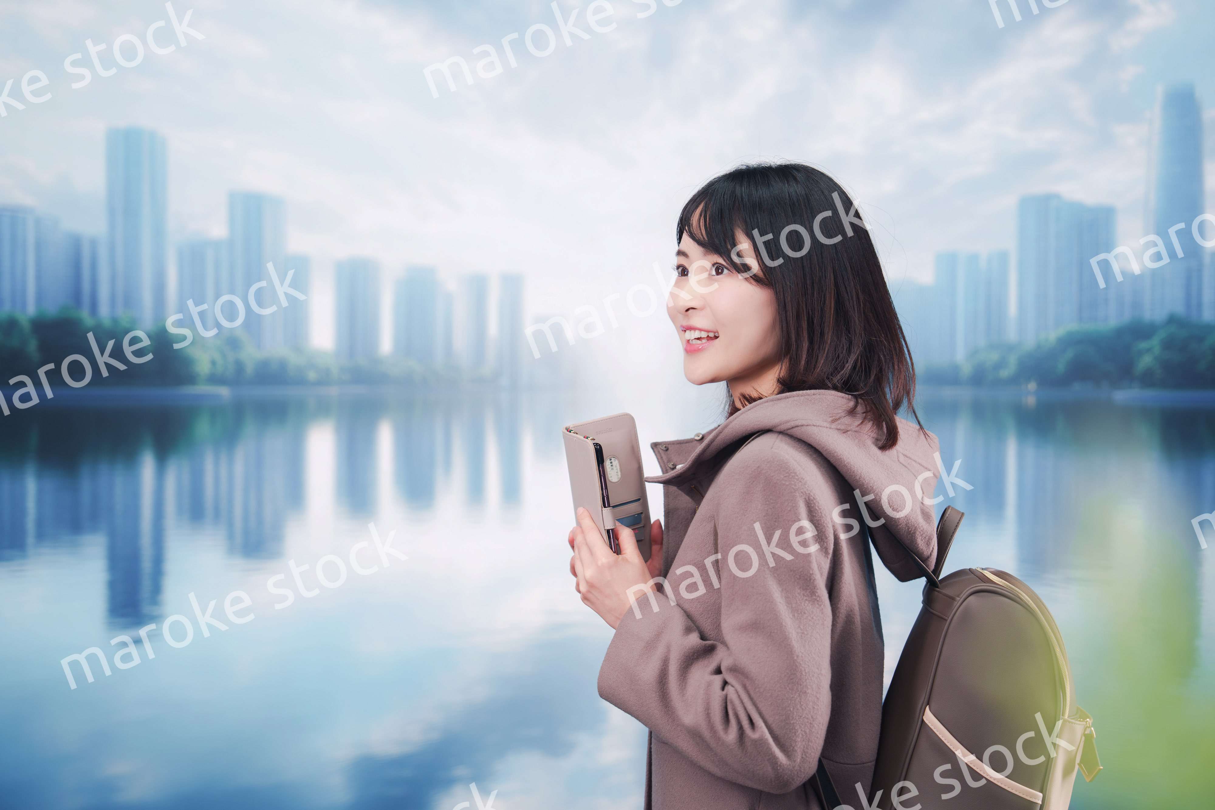 コートを着てスマホを使いながら外を歩く若い女性