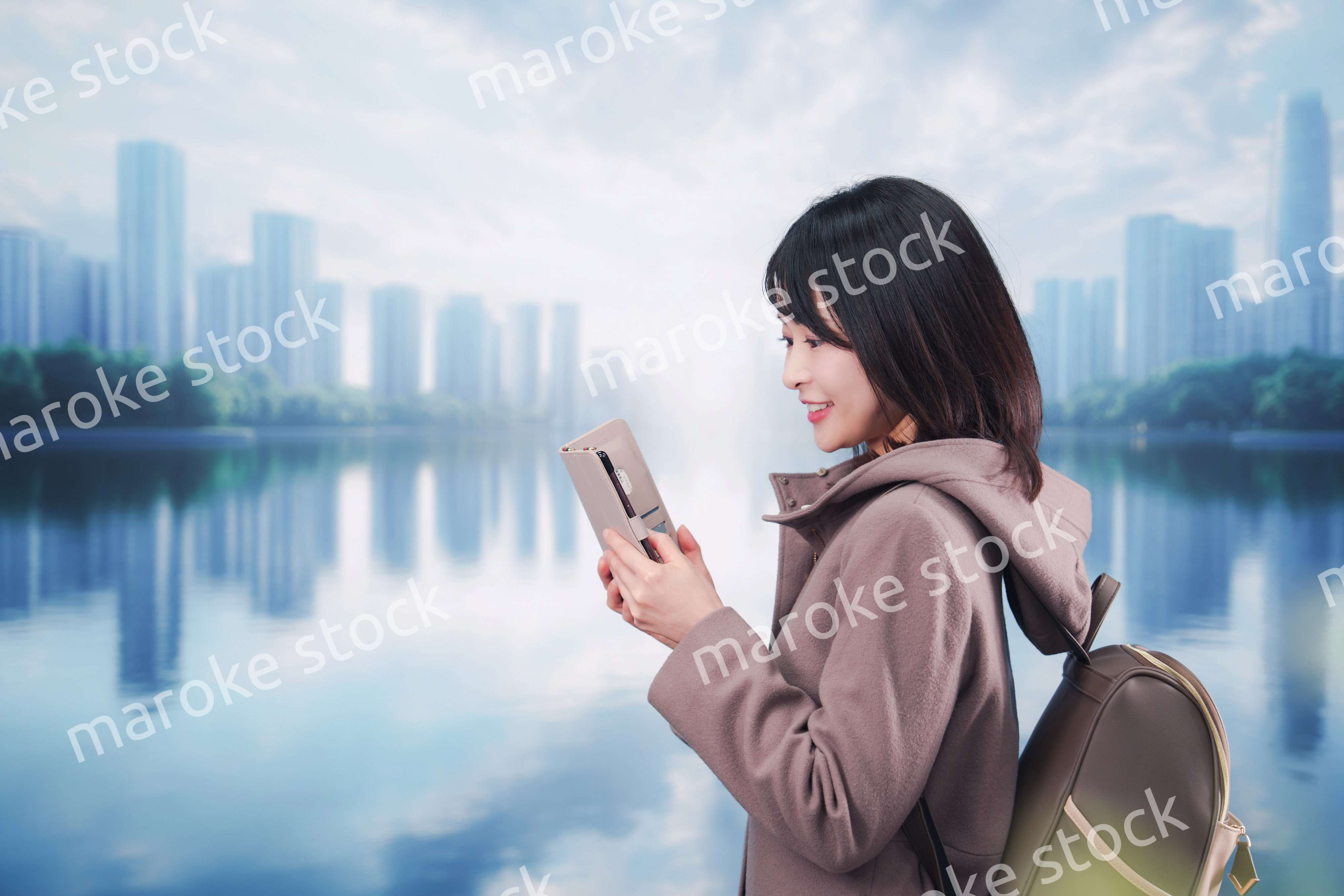 コートを着てスマホを使いながら外を歩く若い女性