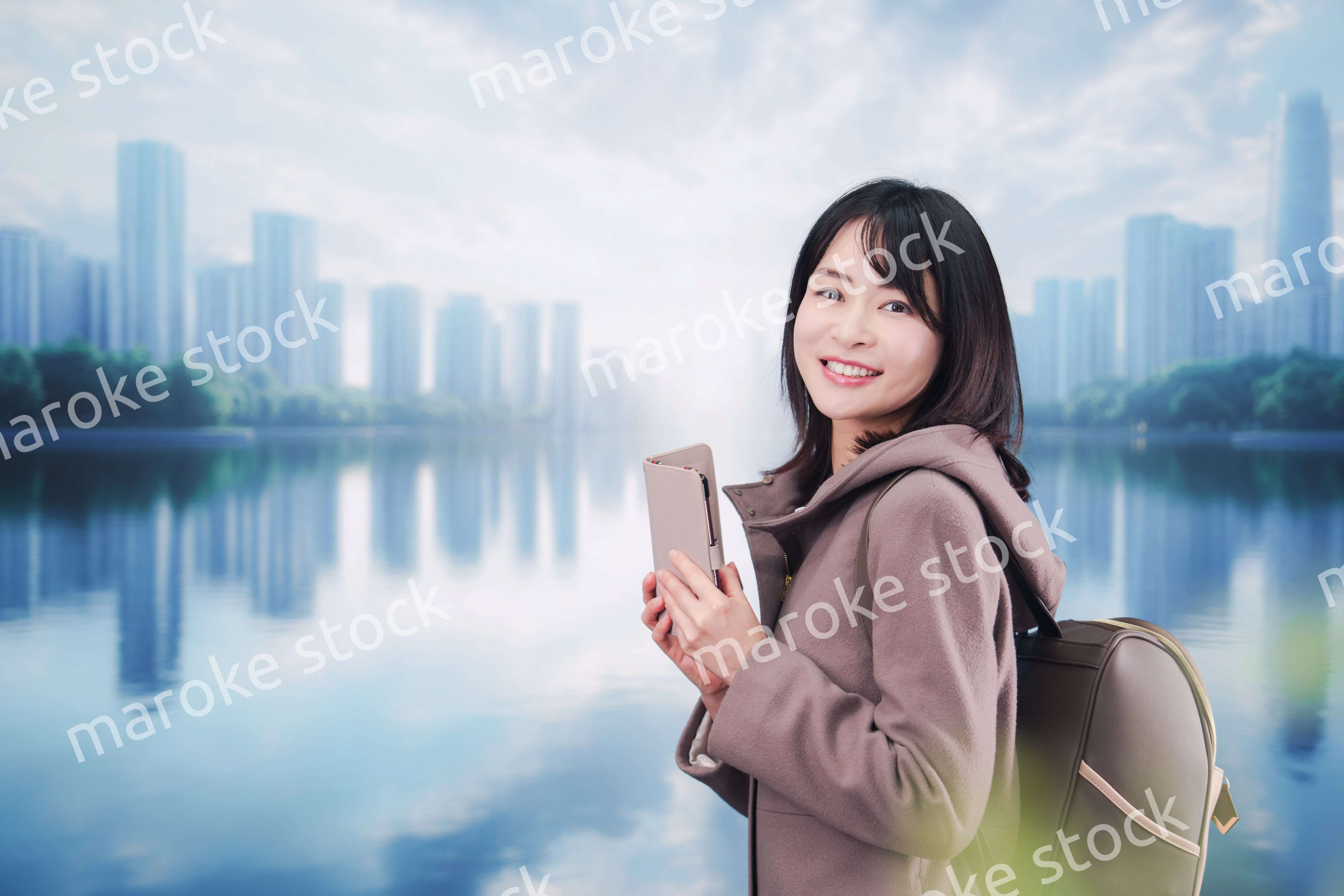 コートを着てスマホを使いながら外を歩く若い女性