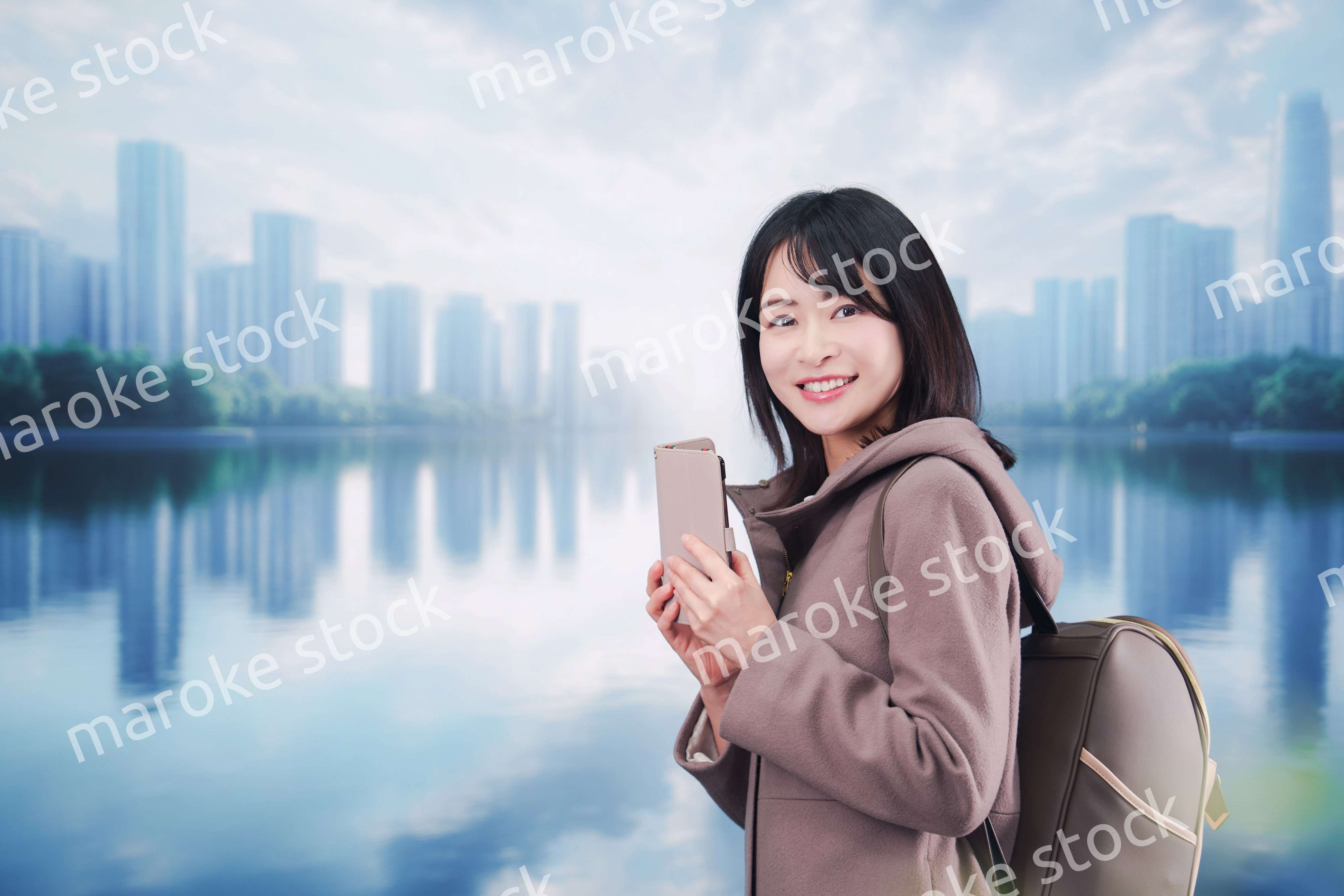 コートを着てスマホを使いながら外を歩く若い女性