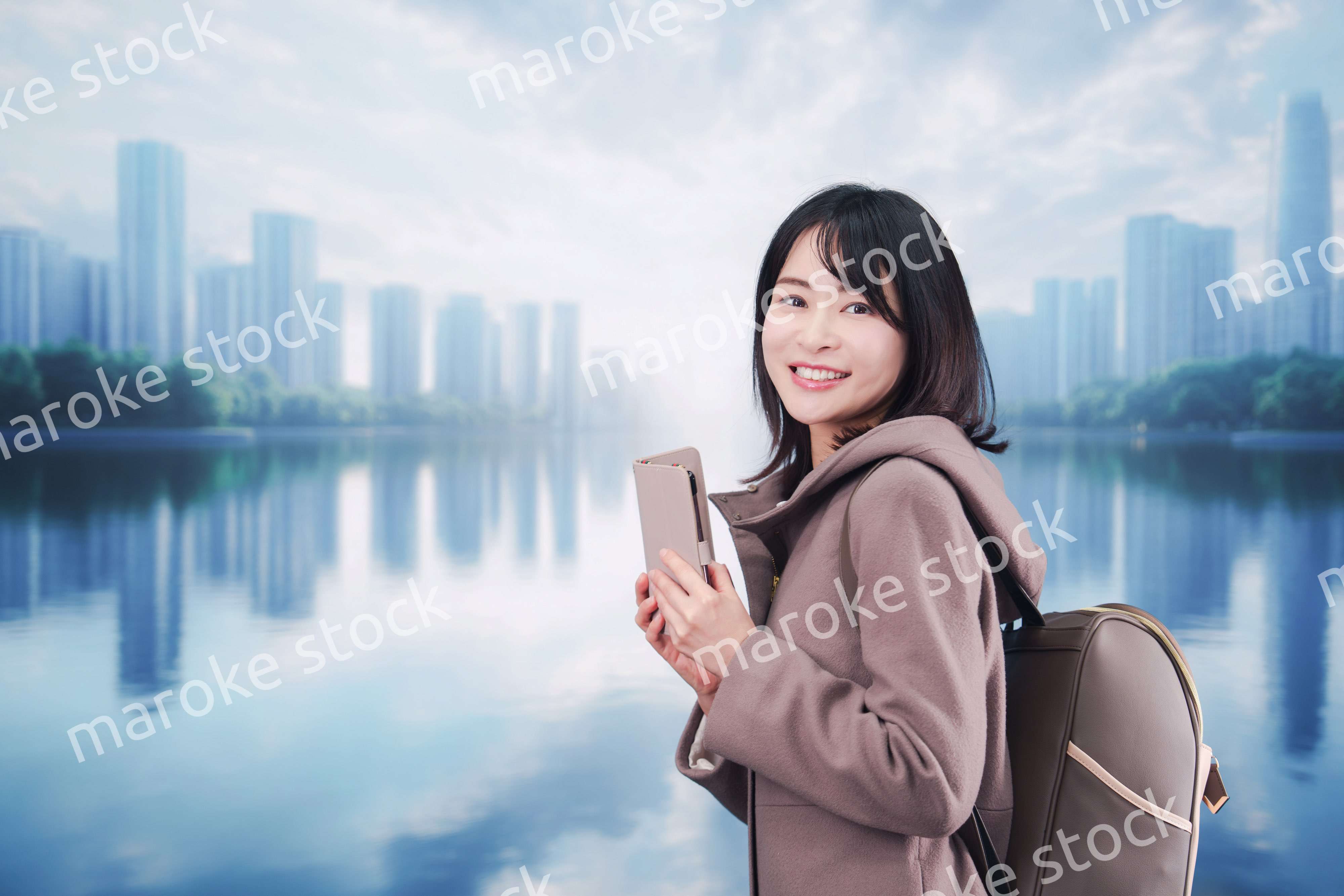 コートを着てスマホを使いながら外を歩く若い女性