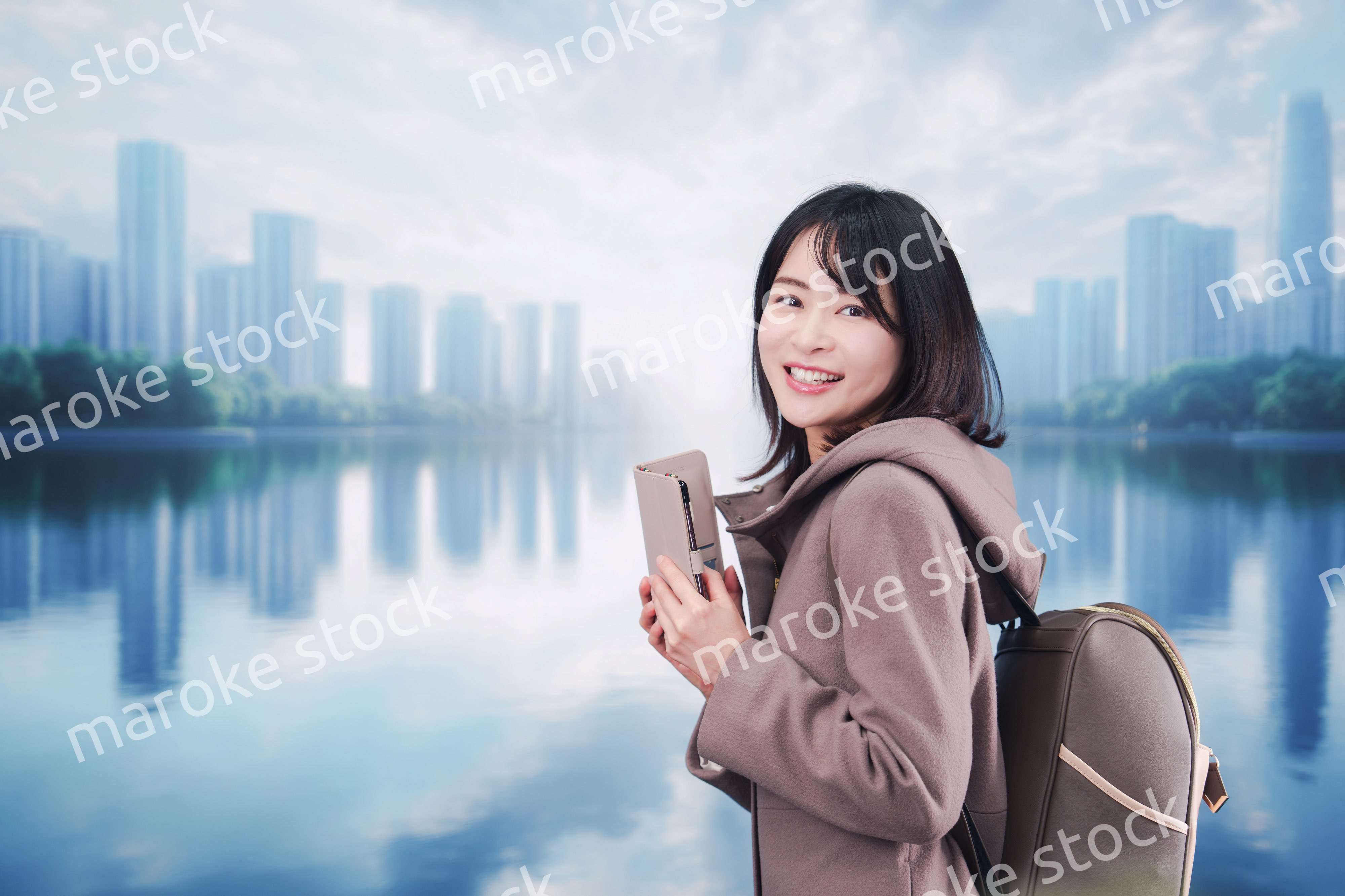 コートを着てスマホを使いながら外を歩く若い女性