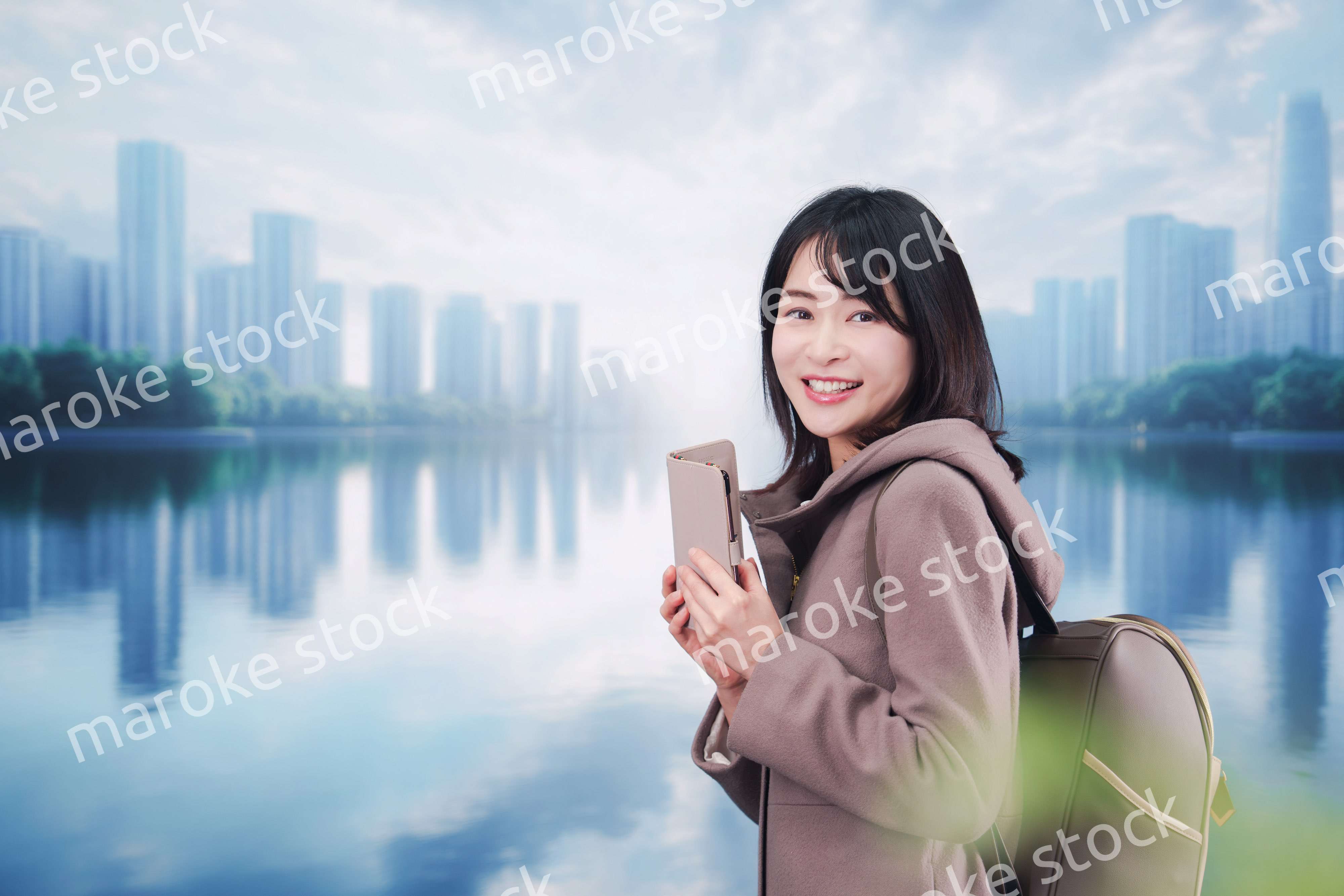 コートを着てスマホを使いながら外を歩く若い女性